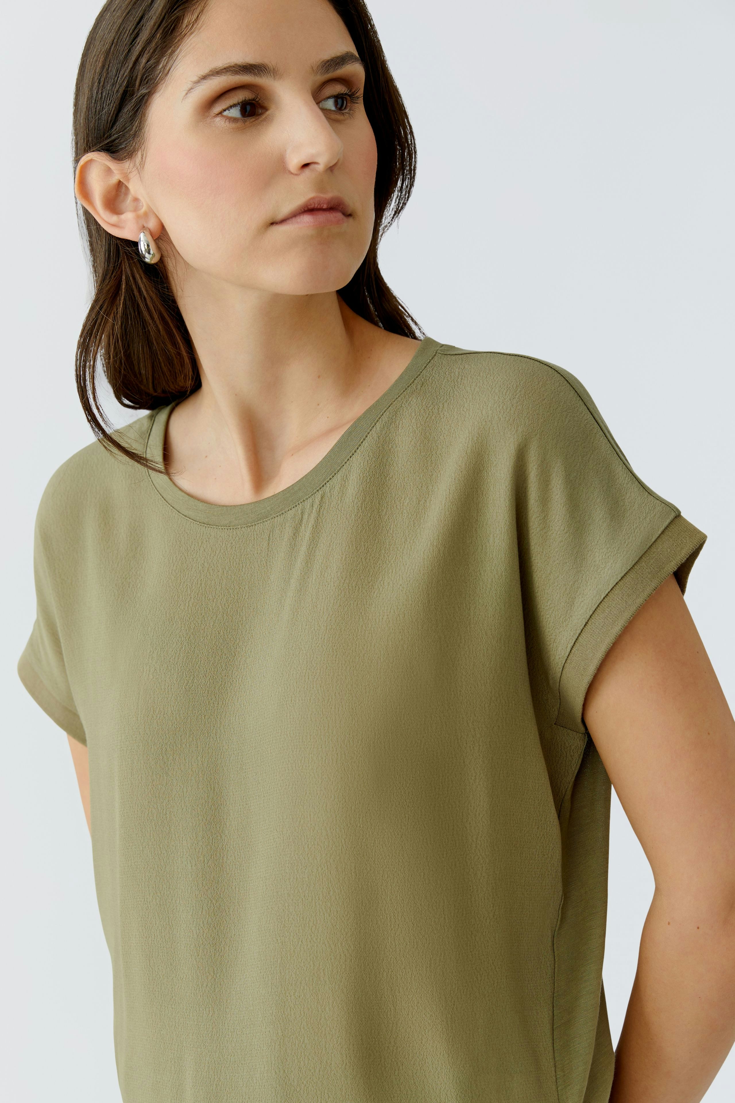 Casual women's blouse shirt in olive green, featuring a relaxed fit and rolled sleeves.