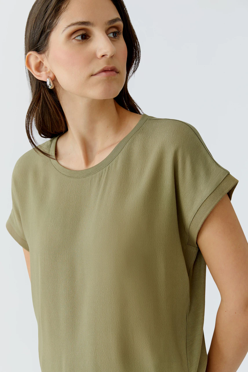 Casual women's blouse shirt in olive green, featuring a relaxed fit and rolled sleeves.