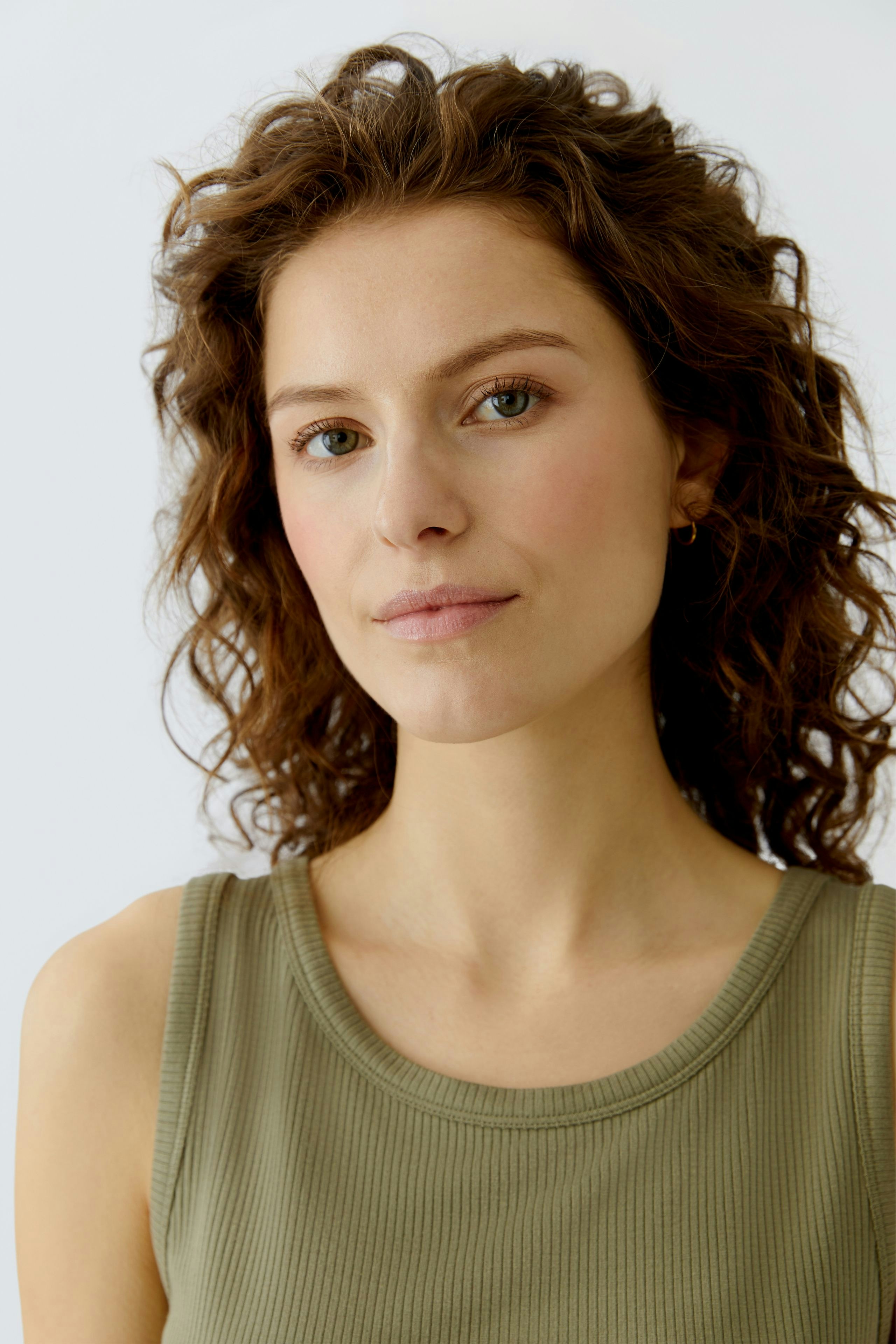 Casual women's top: Young woman in a green ribbed tank top, showcasing a relaxed and comfortable style.