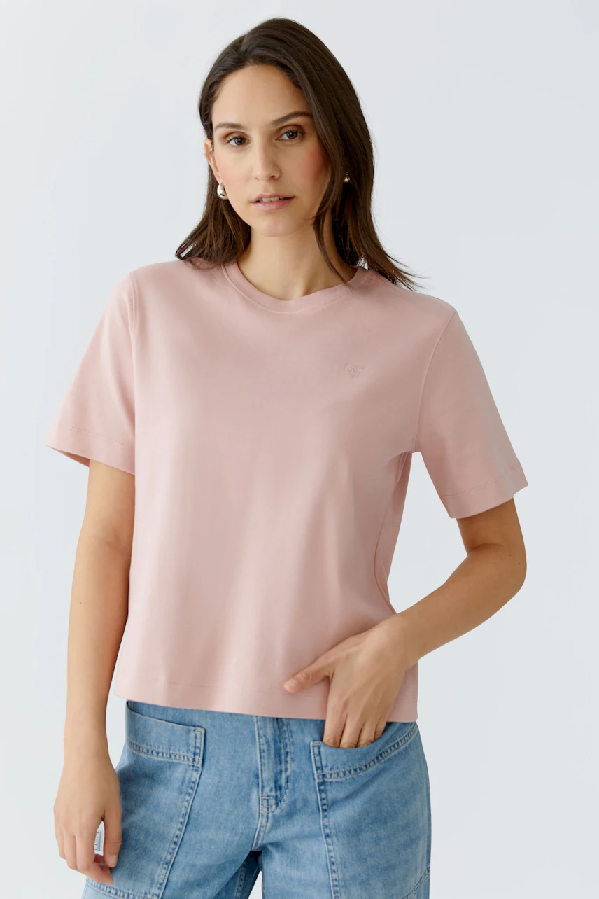 Damen-T-Shirt in zartem Rosa: Frau trägt ein schlichtes, lässiges T-Shirt mit kurzen Ärmeln.