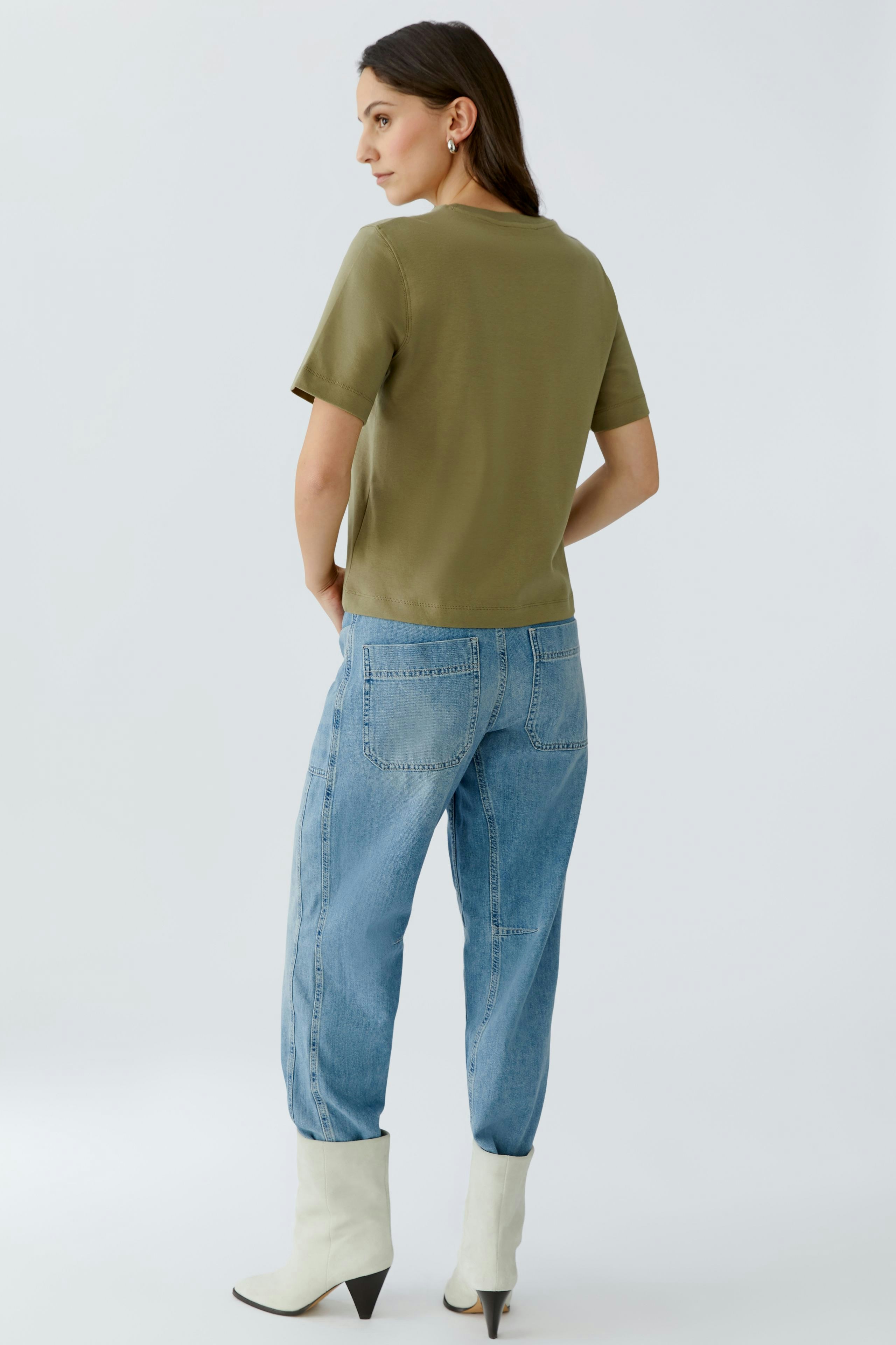 Casual women's T-shirt: A woman in a green T-shirt paired with relaxed blue jeans, showcasing a laid-back style.