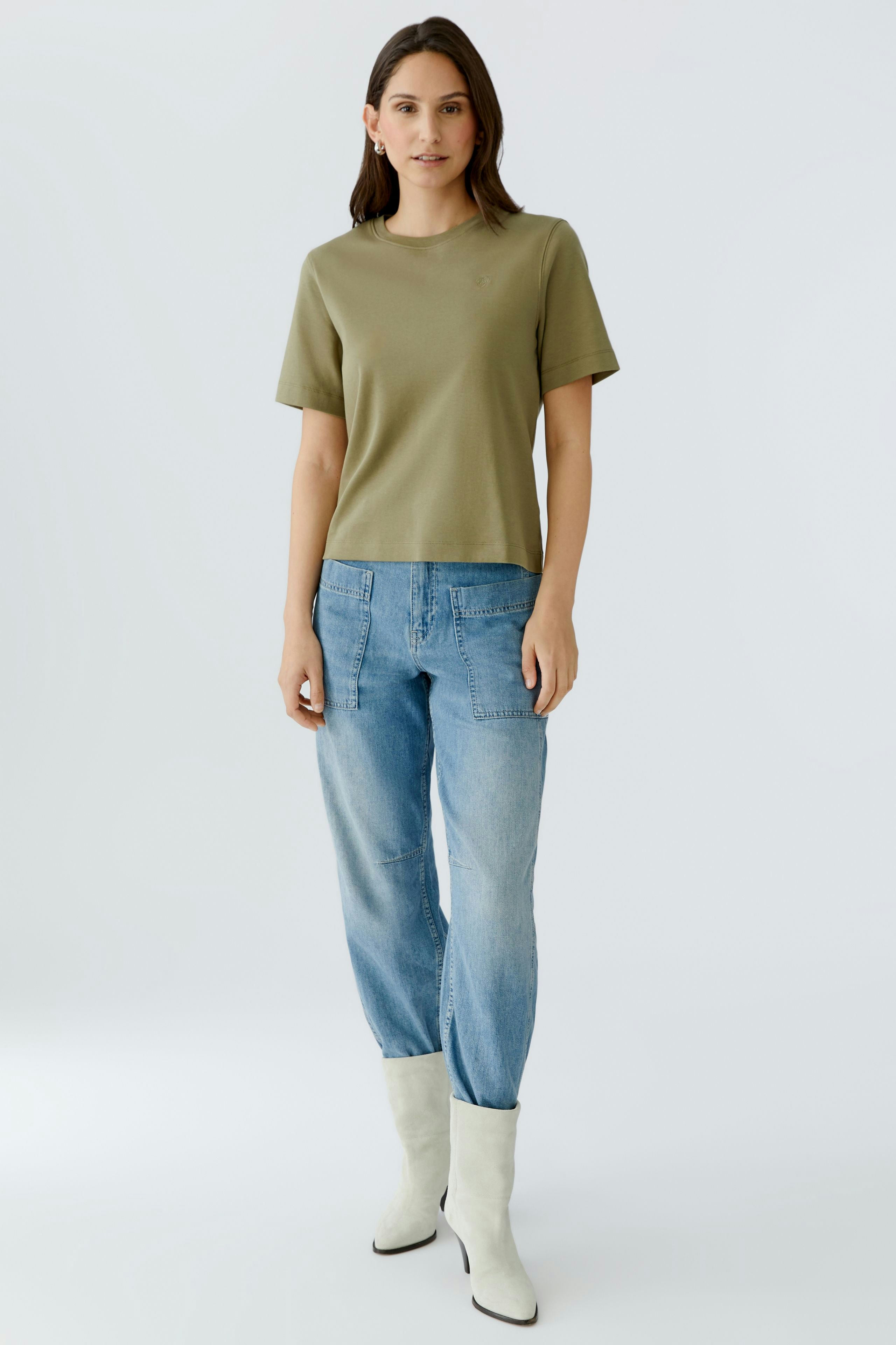 Casual women's T-shirt: A woman in a green T-shirt paired with light blue jeans and white boots.