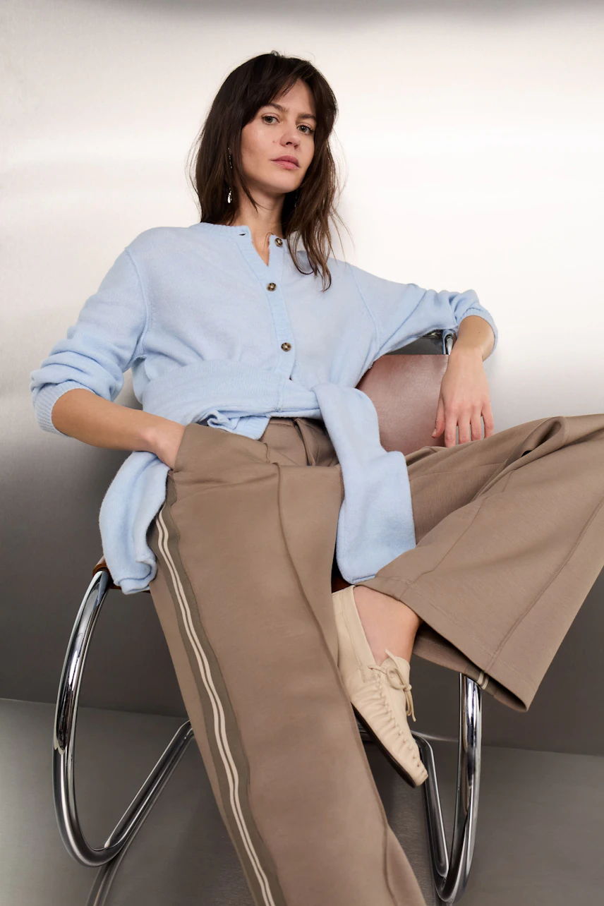 Casual women's cardigan: A woman in a light blue cardigan with buttons, paired with wide beige trousers.