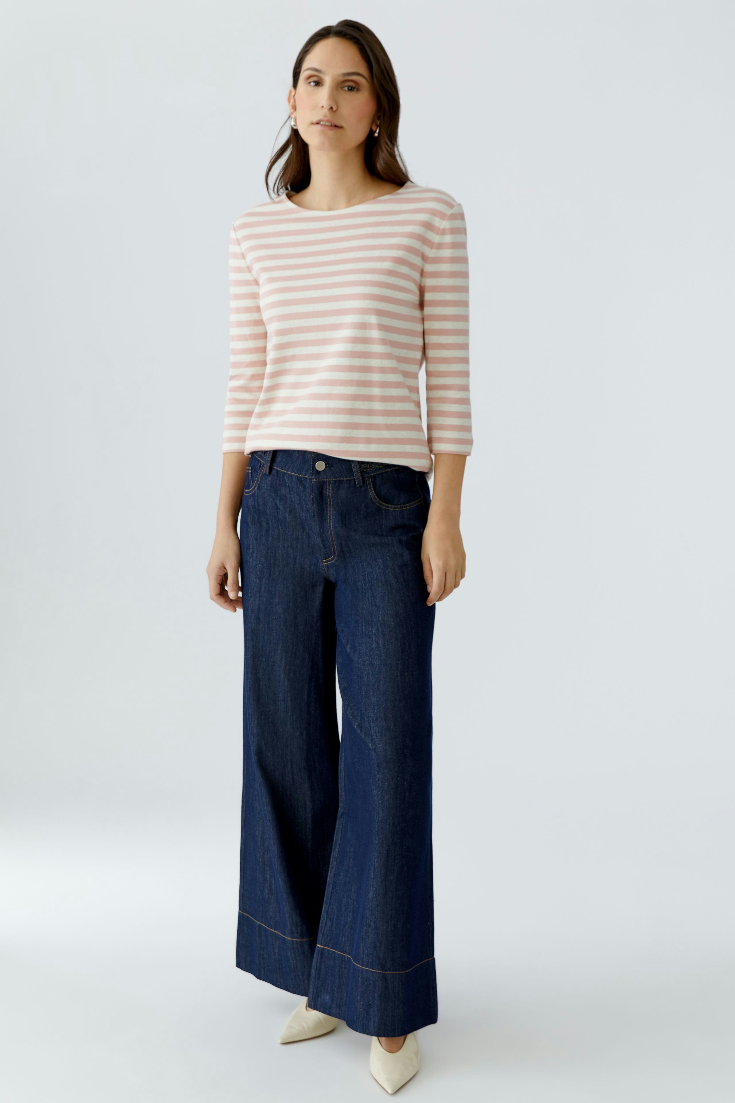 Casual women's T-shirt: Woman in a striped top paired with wide-leg jeans, standing confidently.