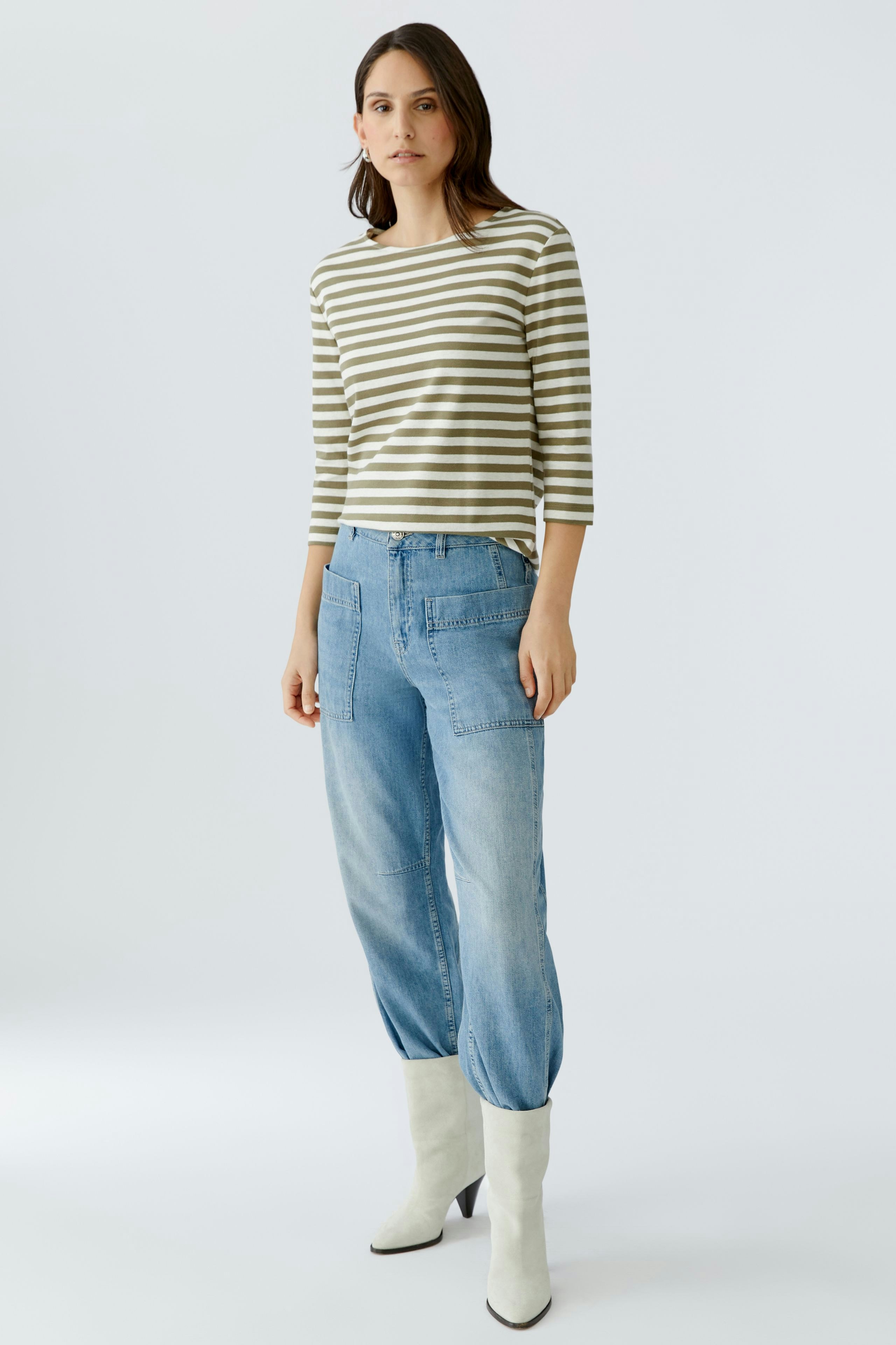 Casual women's T-shirt: Woman in a striped top paired with relaxed-fit jeans and stylish boots.