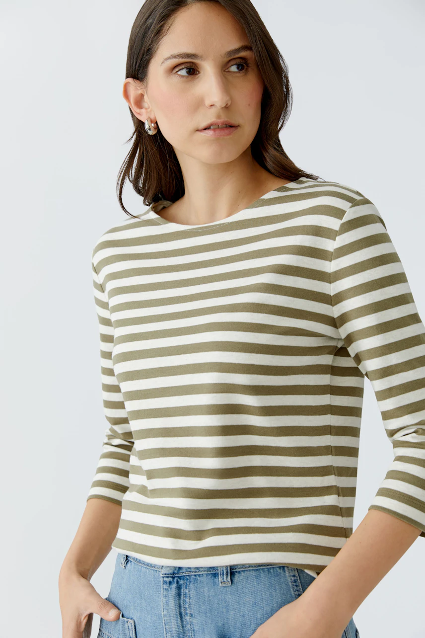 Damen-T-Shirt mit Streifen: Frau trägt ein olivgrünes T-Shirt mit weißen Streifen und lässigem Schnitt.