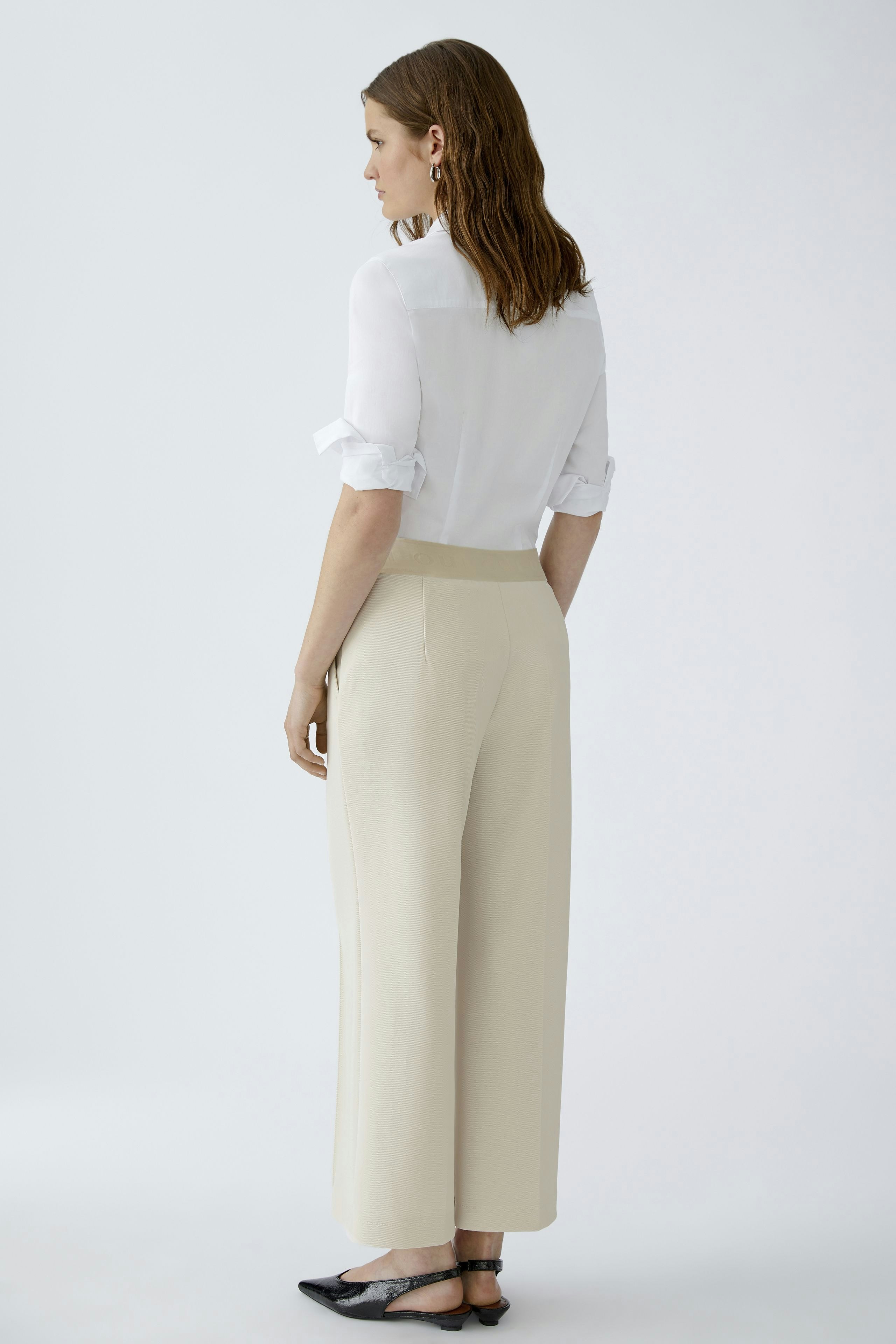 Casual women's culottes: A woman in beige culottes with a white shirt, showcasing a relaxed fit.