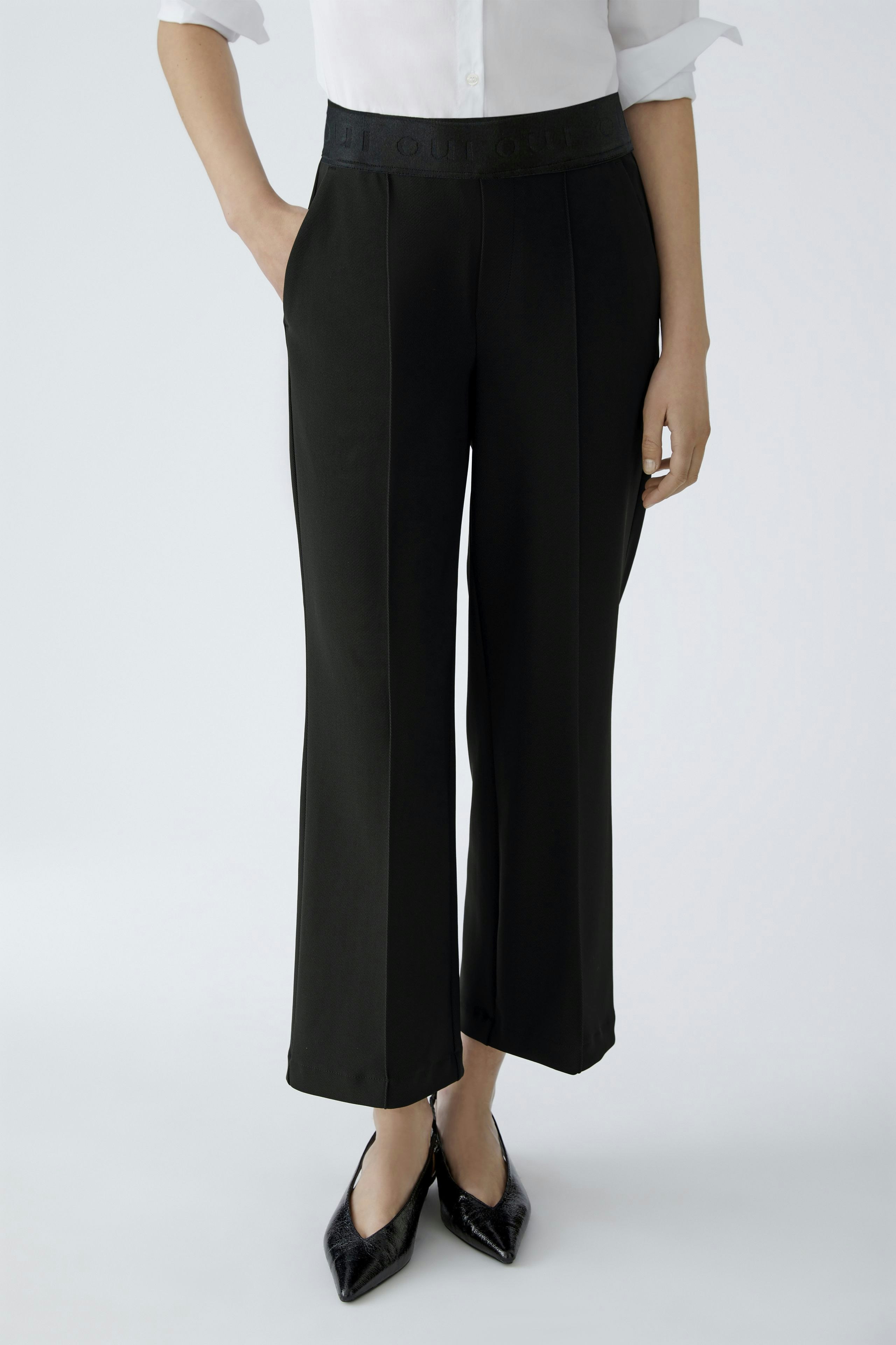 Modern culotte: Woman in black wide-leg pants with a comfortable waistband, paired with a classic shirt.