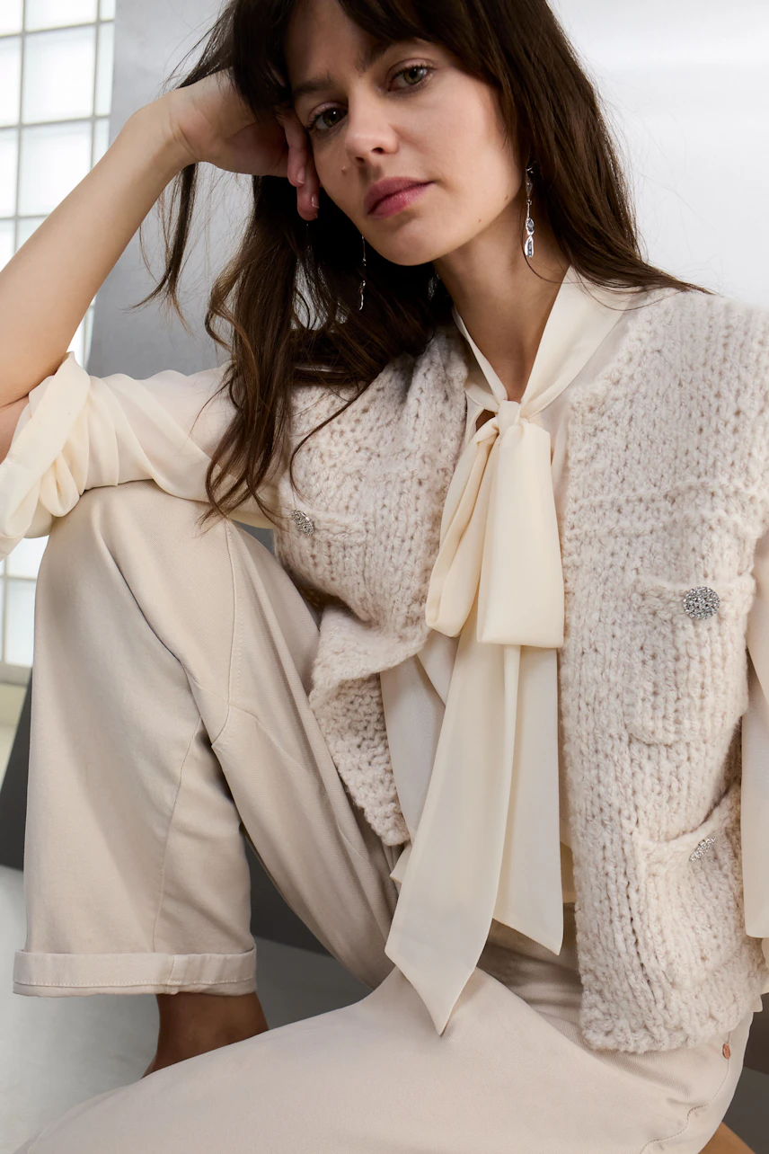 Casual women's cardigan: A woman in a light knitted cardigan over a blouse, sitting comfortably.