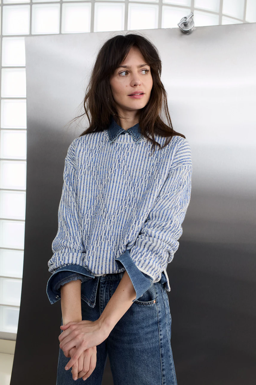 Casual women's pullover: A woman in a striped pullover layered over a denim shirt, looking relaxed.