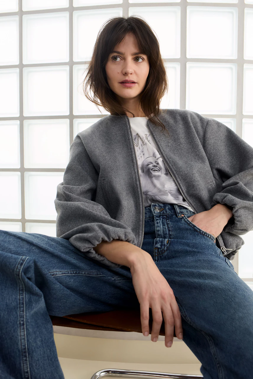 Casual women's T-shirt: A woman in a graphic tee paired with a cozy bomber jacket and relaxed jeans.