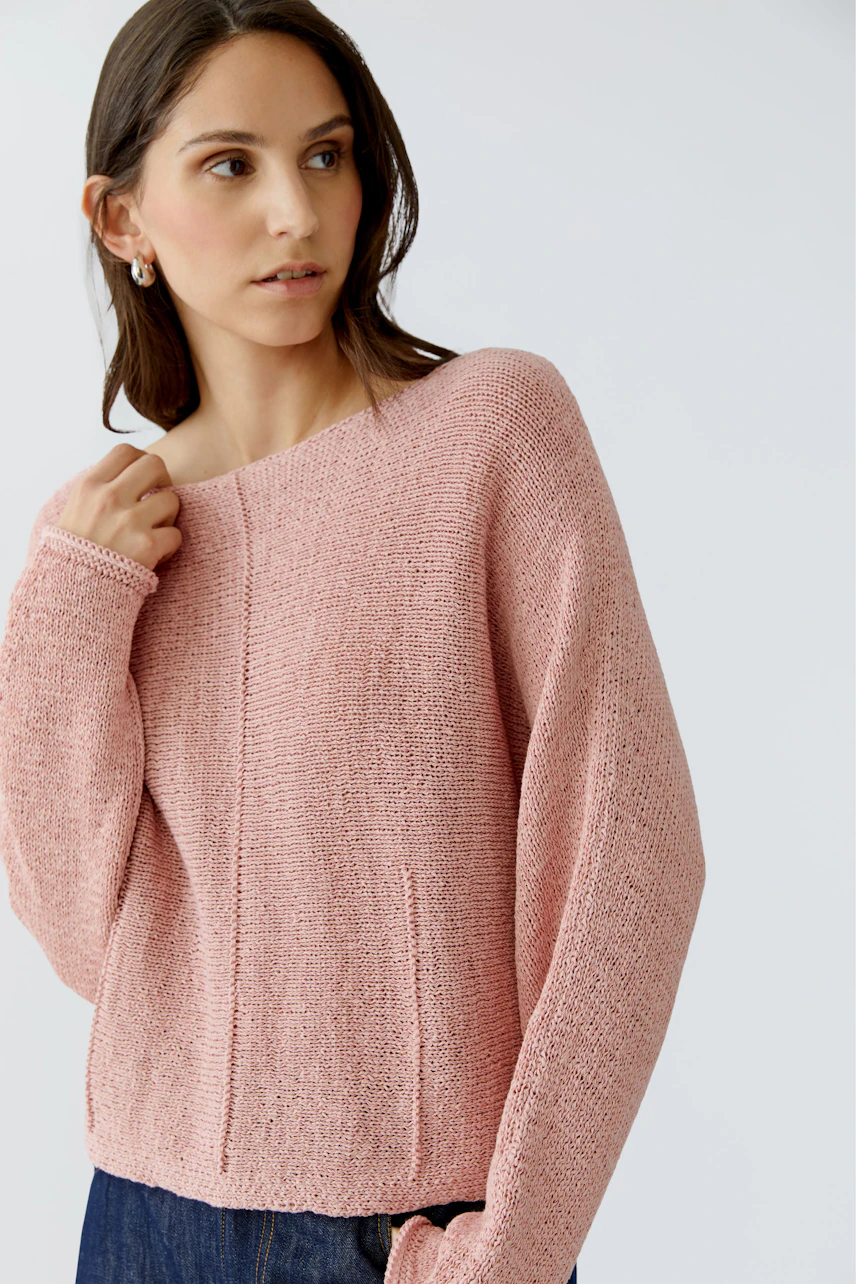 Damen-Pullover: Junge Frau in einem rosafarbenen, lässigen Strickpullover mit weitem Schnitt.