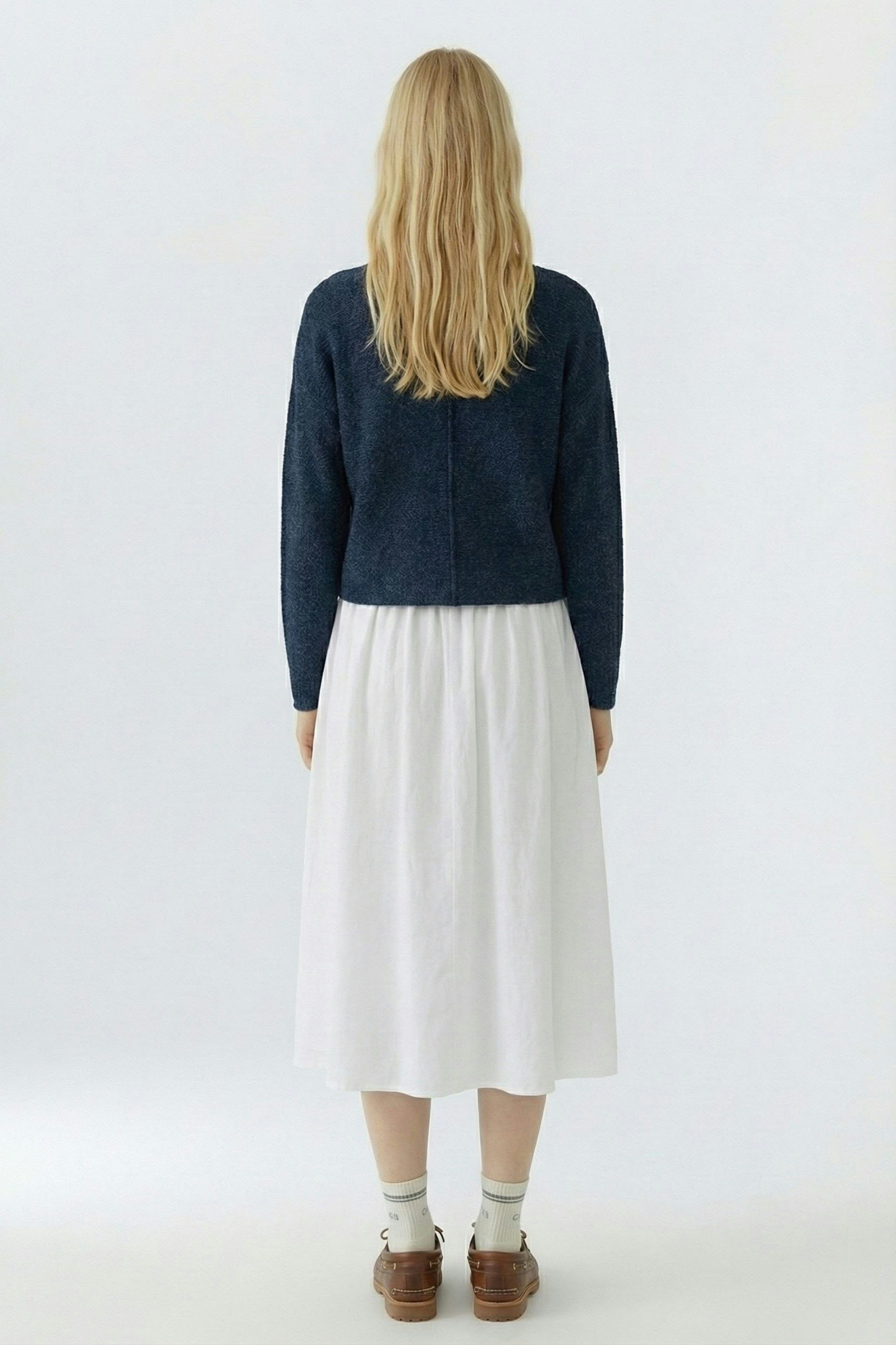 Damen-Pullover: Frau mit langen Haaren trägt einen blauen Strickpullover und einen weißen Rock.