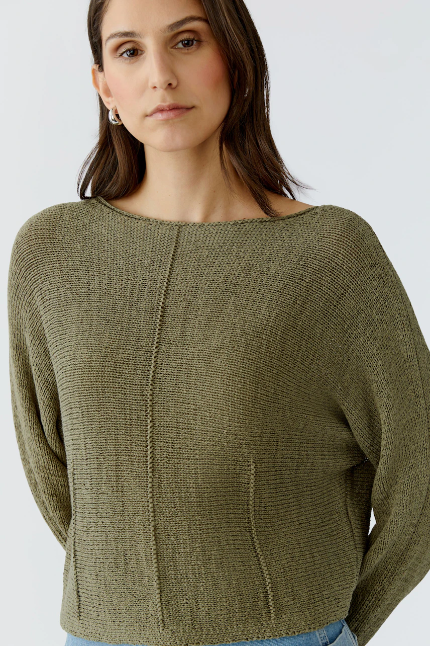 Casual women's pullover: Woman in a relaxed olive green knit pullover with a wide neckline.