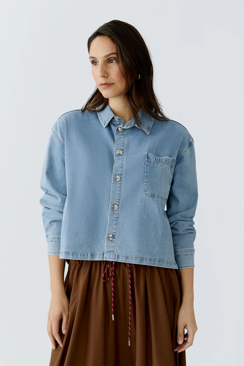 Casual women's blouse: Woman in a light blue denim blouse with buttons and a relaxed fit.