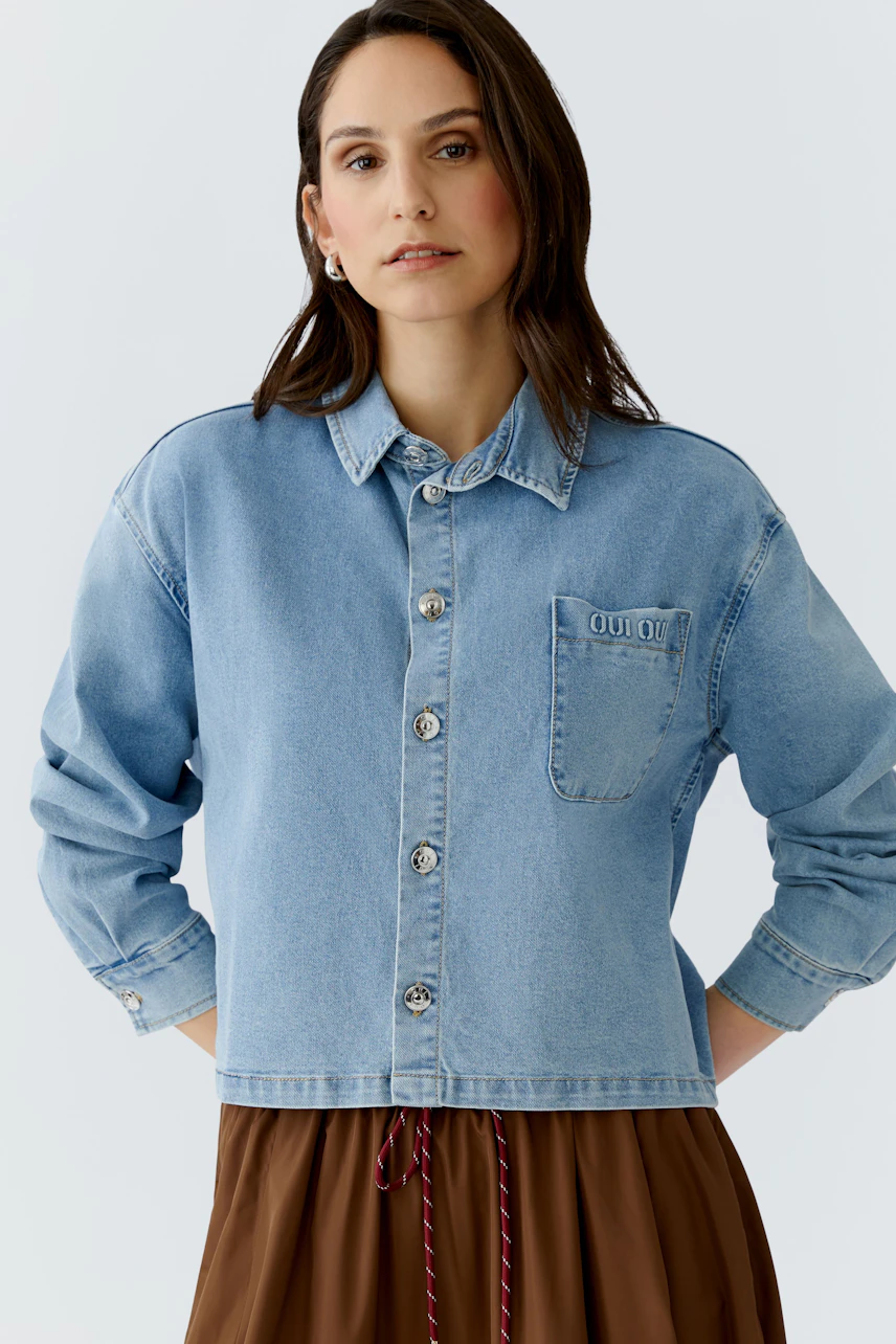 Casual women's blouse: A woman in a light blue denim blouse with a pocket, styled with a brown skirt.