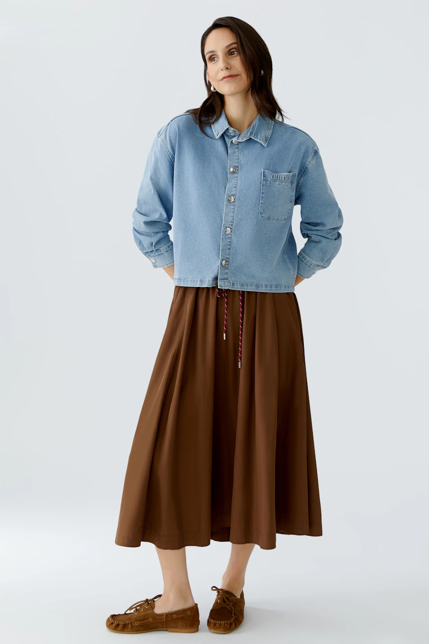 Casual women's blouse: A woman in a light blue denim blouse with a relaxed fit and brown skirt.