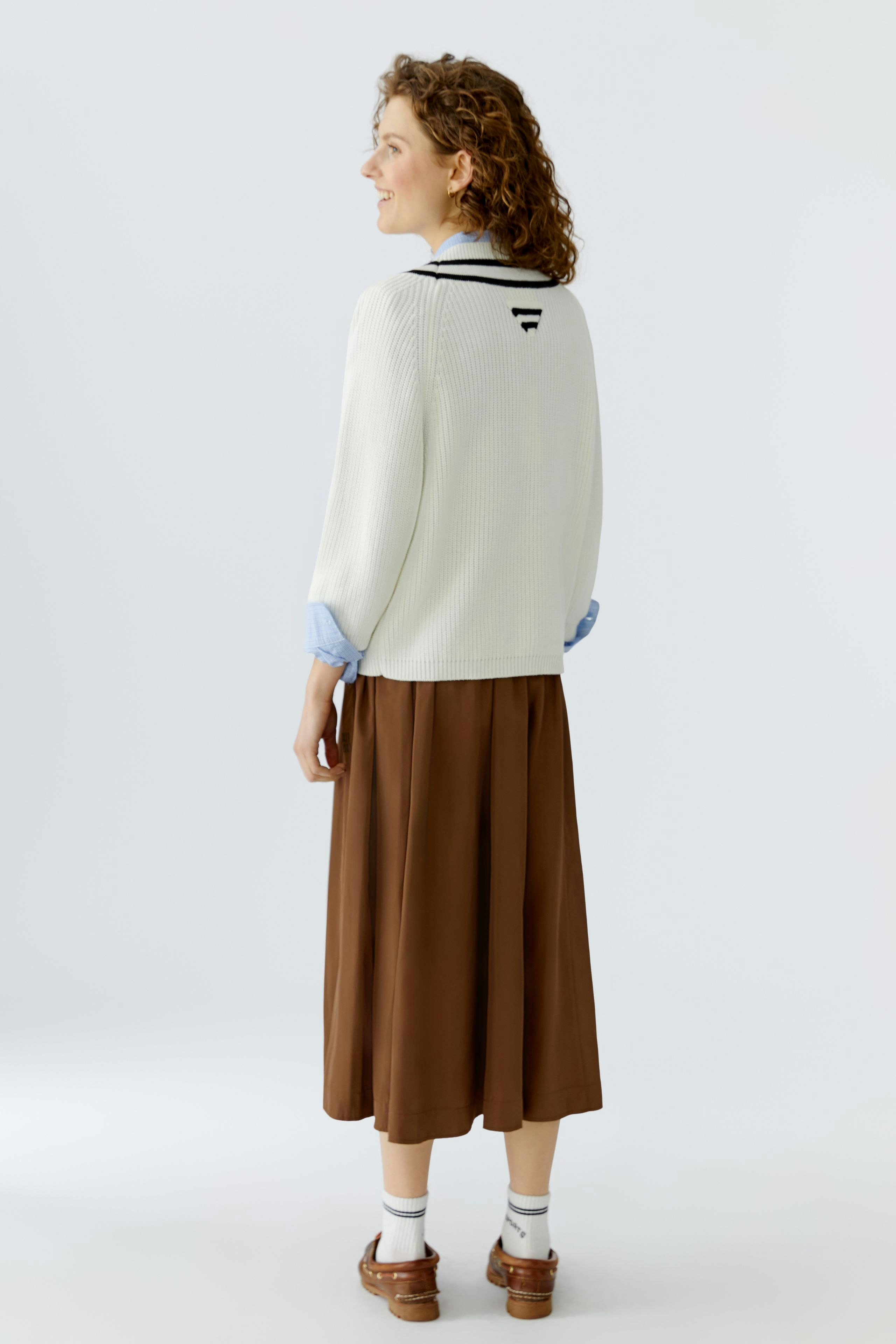 Casual women's pullover: A woman in a light pullover with a relaxed fit, paired with a brown skirt.