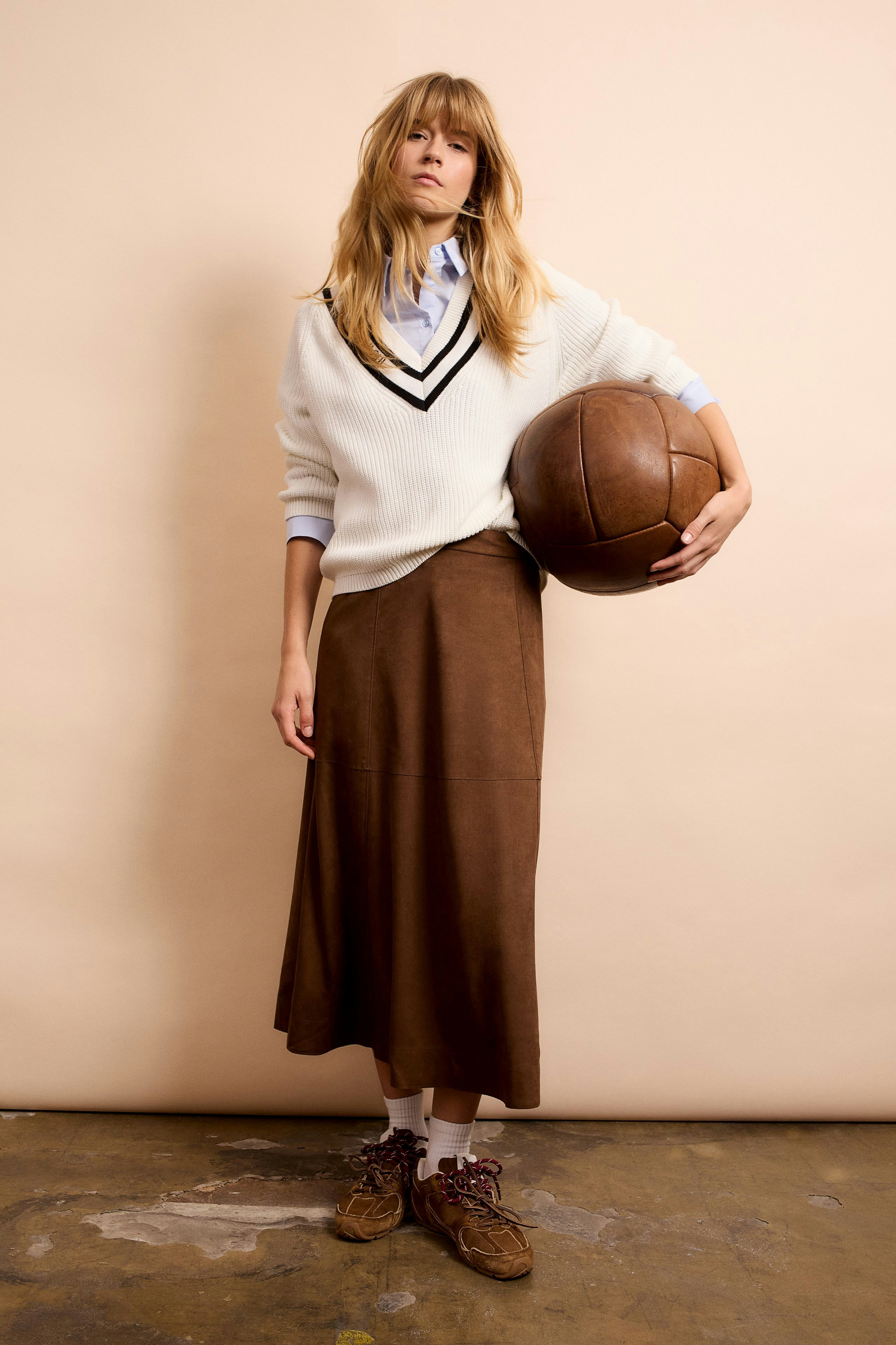 Casual women's pullover: Young woman in a white pullover with a sporty design, holding a basketball.