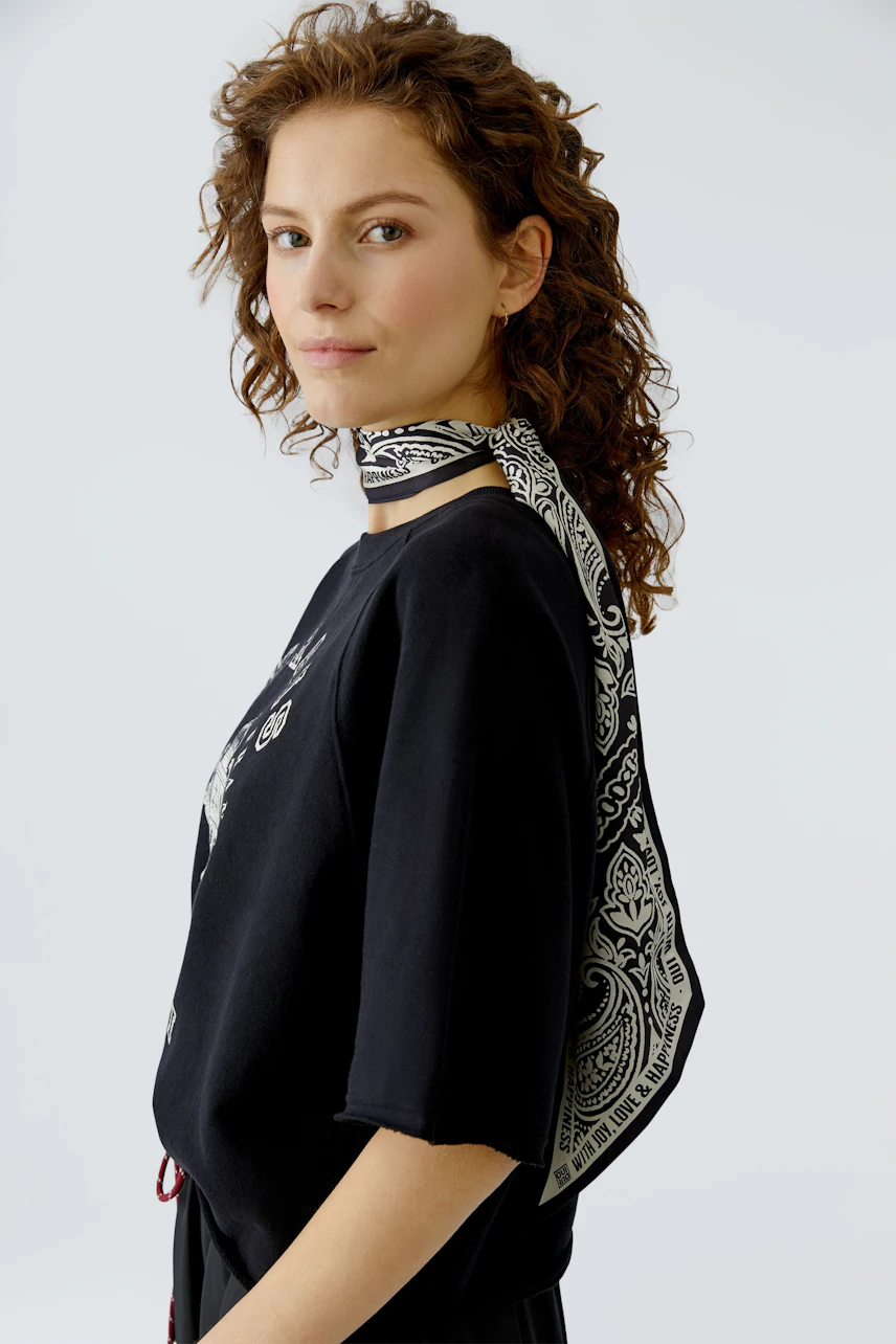 Stylish scarf: Woman wearing a patterned black and white scarf, adding a unique touch to her outfit.