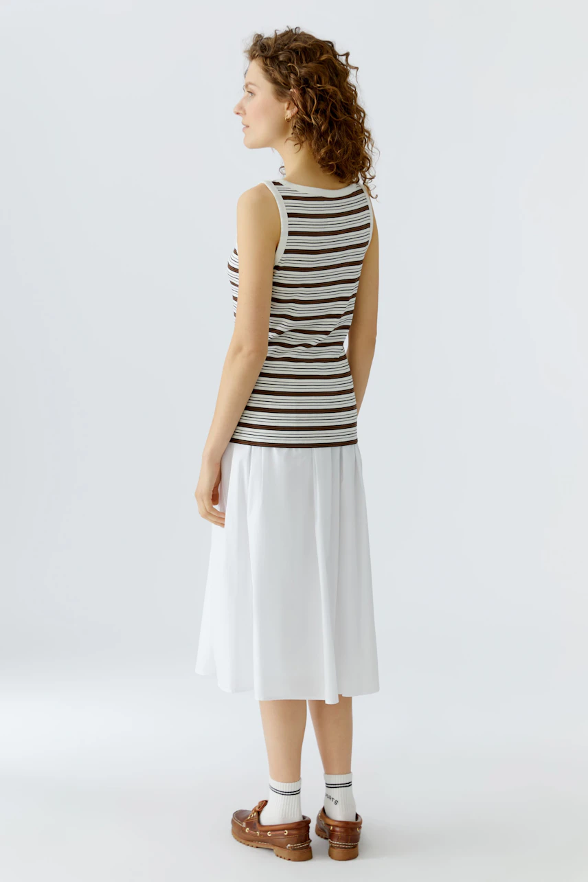 Casual women's tank top: A woman in a striped tank top paired with a white skirt, showcasing a relaxed style.