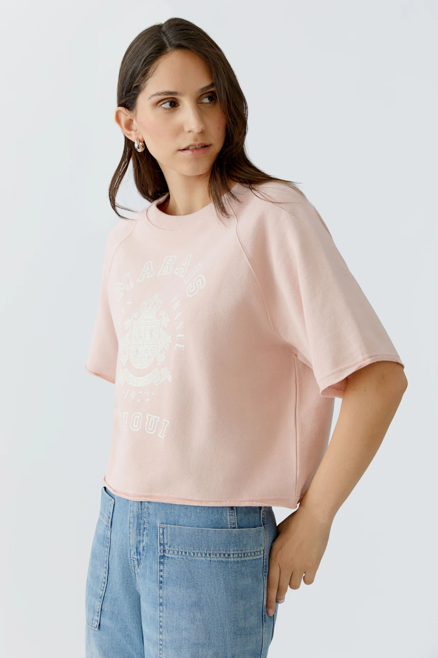 Bequemer Damen-Sweatshirt: Frau in rosa, lässigem Pullover mit Print und weiten Ärmeln.