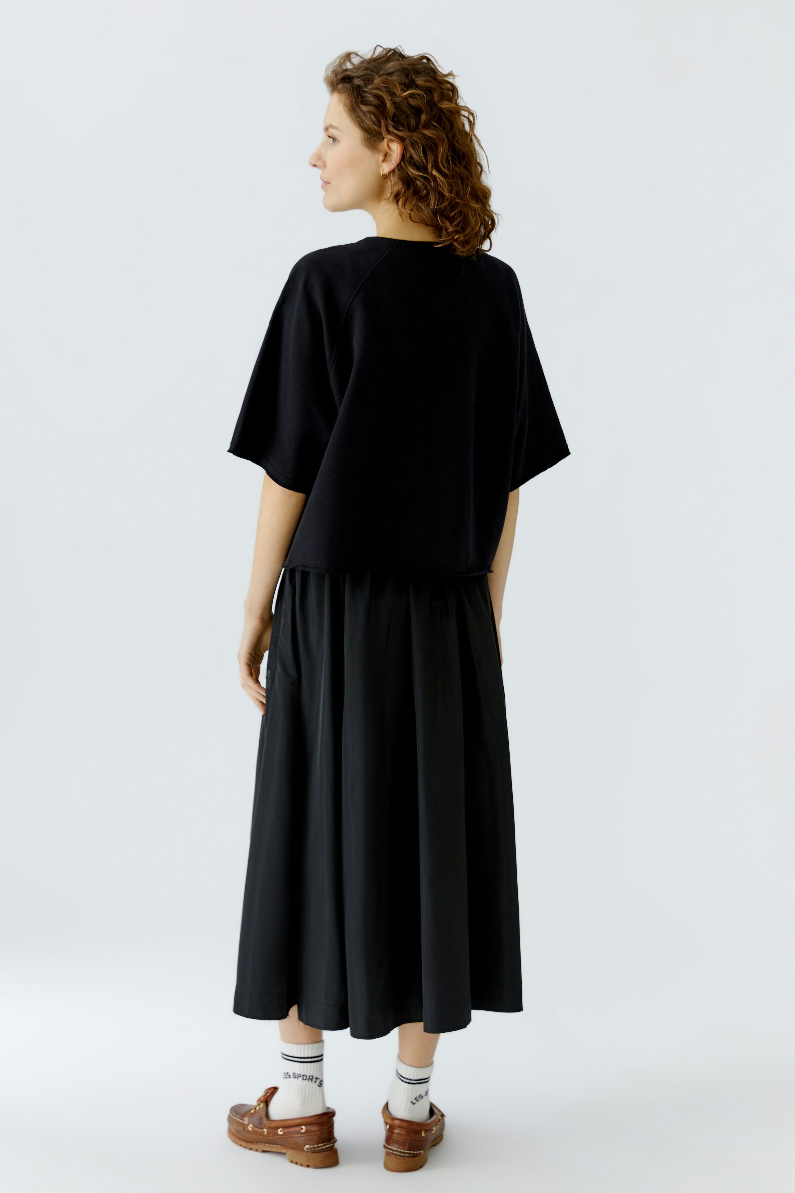 Casual women's pullover: A woman in a black oversized pullover paired with a flowing skirt.