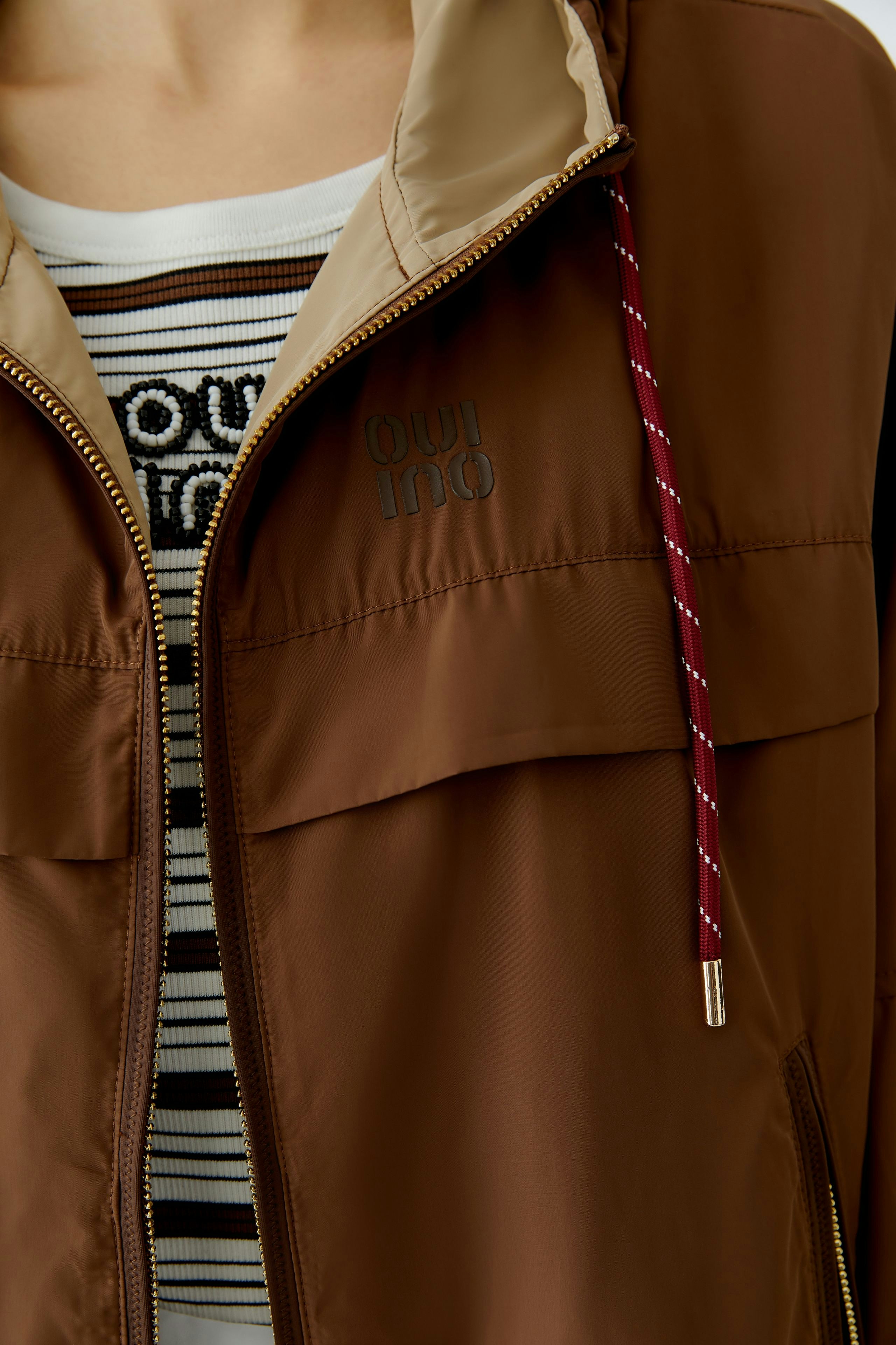 Praktische Outdoorjacke: Frau in brauner Jacke mit beigem Kragen und gestreiftem Shirt.