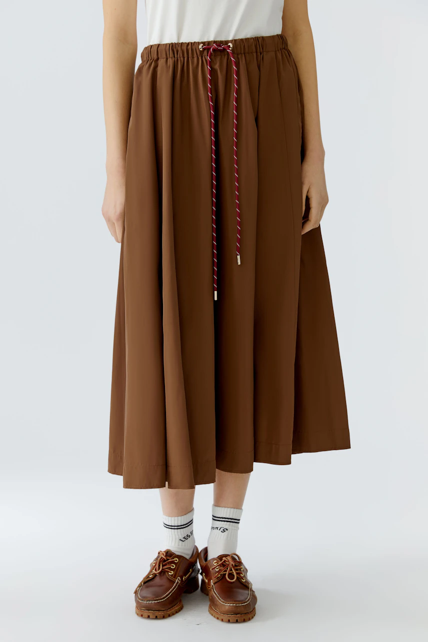 Casual A-line skirt: Woman in a brown A-line skirt with an elastic waistband and drawstring.