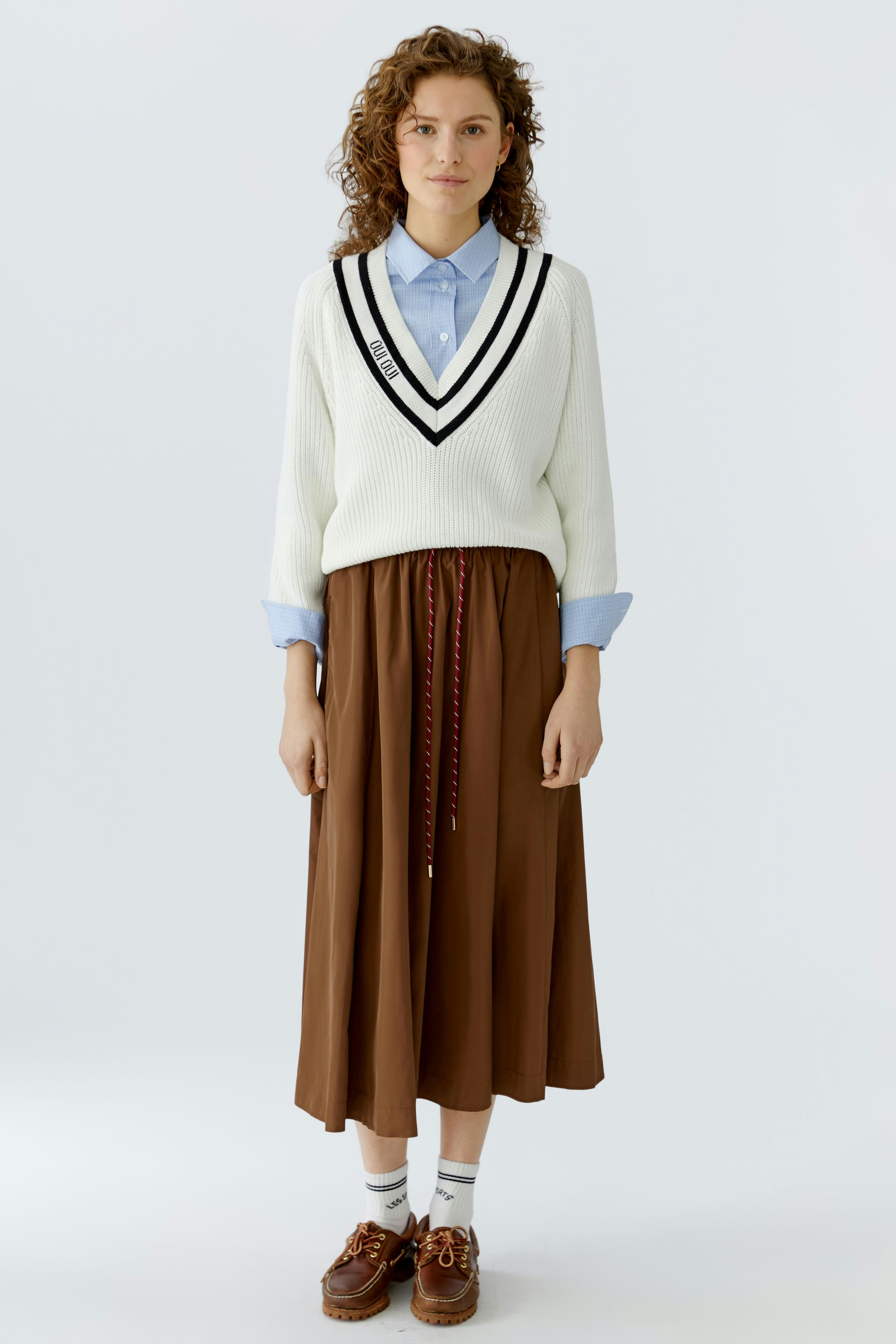 A-line skirt: Woman in a white pullover and brown skirt, showcasing a casual and stylish look.