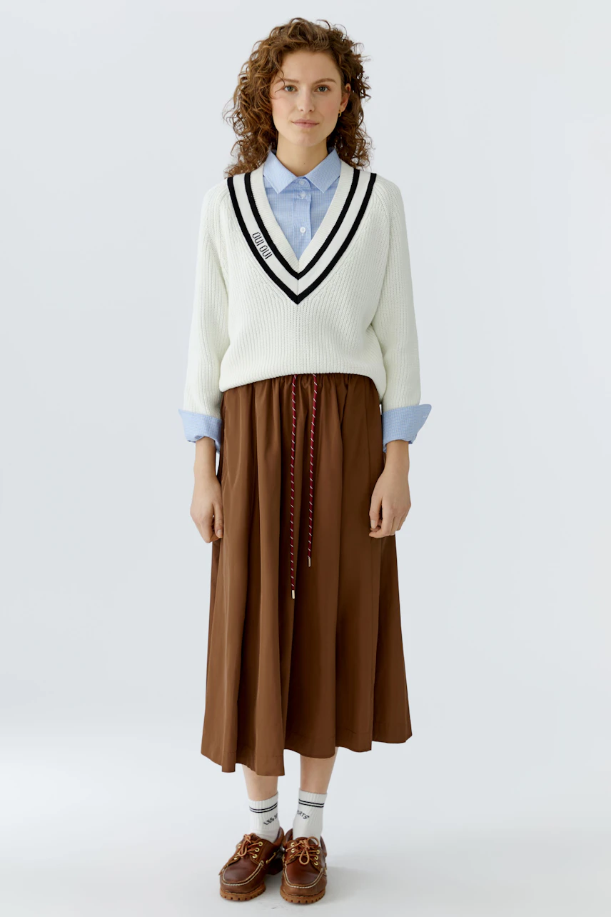 A-line skirt: Woman in a white pullover and brown skirt, showcasing a casual and stylish look.
