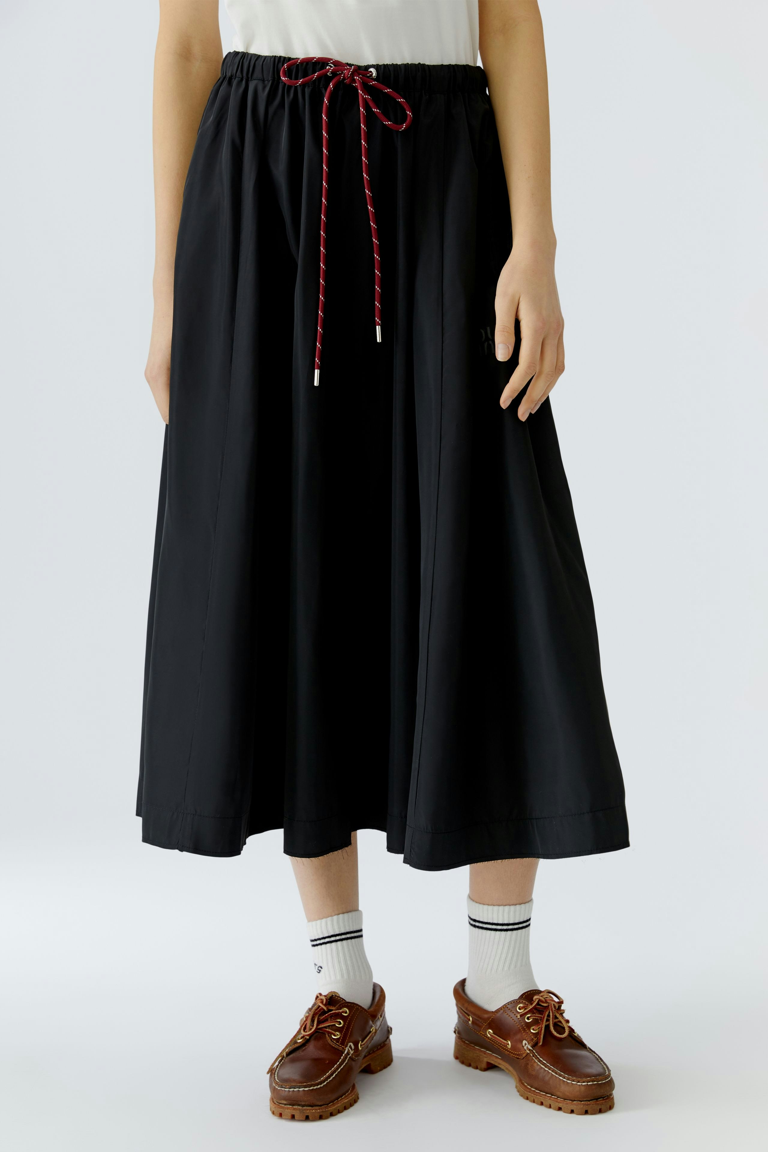 Casual A-line skirt: Woman in a black skirt with a drawstring waist, paired with stylish shoes.
