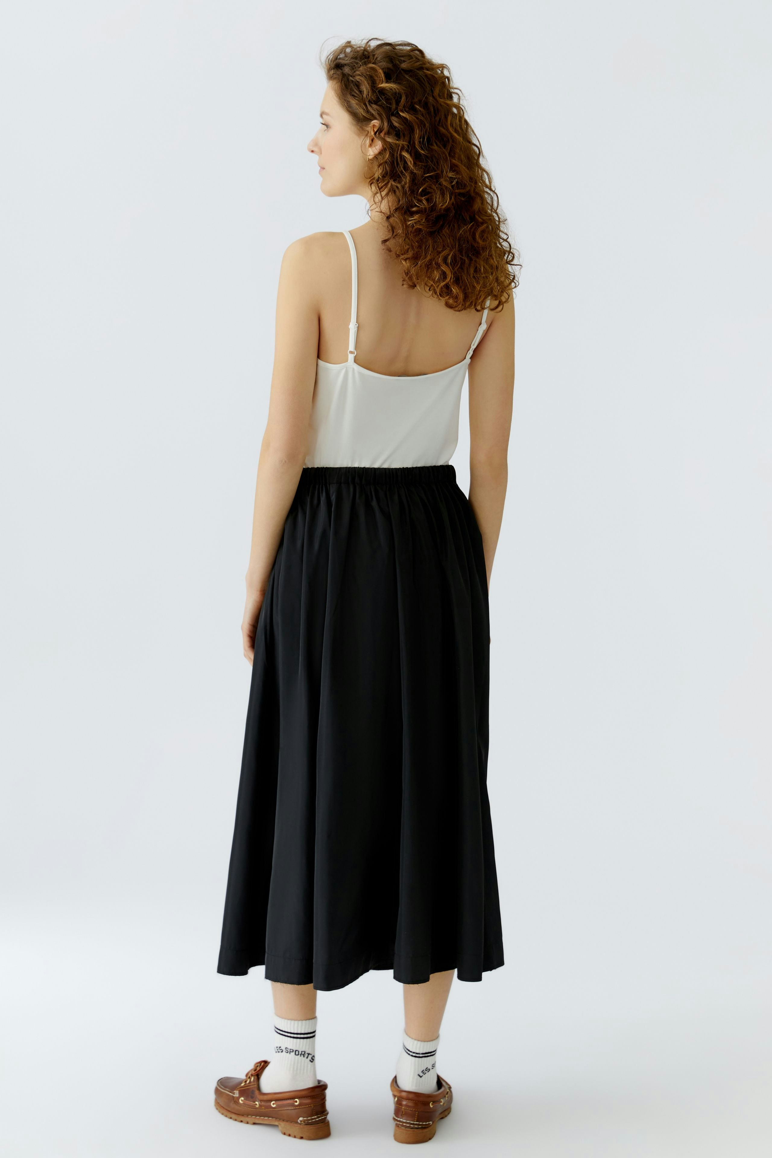 Casual A-line skirt: Woman in a black A-line skirt with a relaxed fit, paired with a simple top.