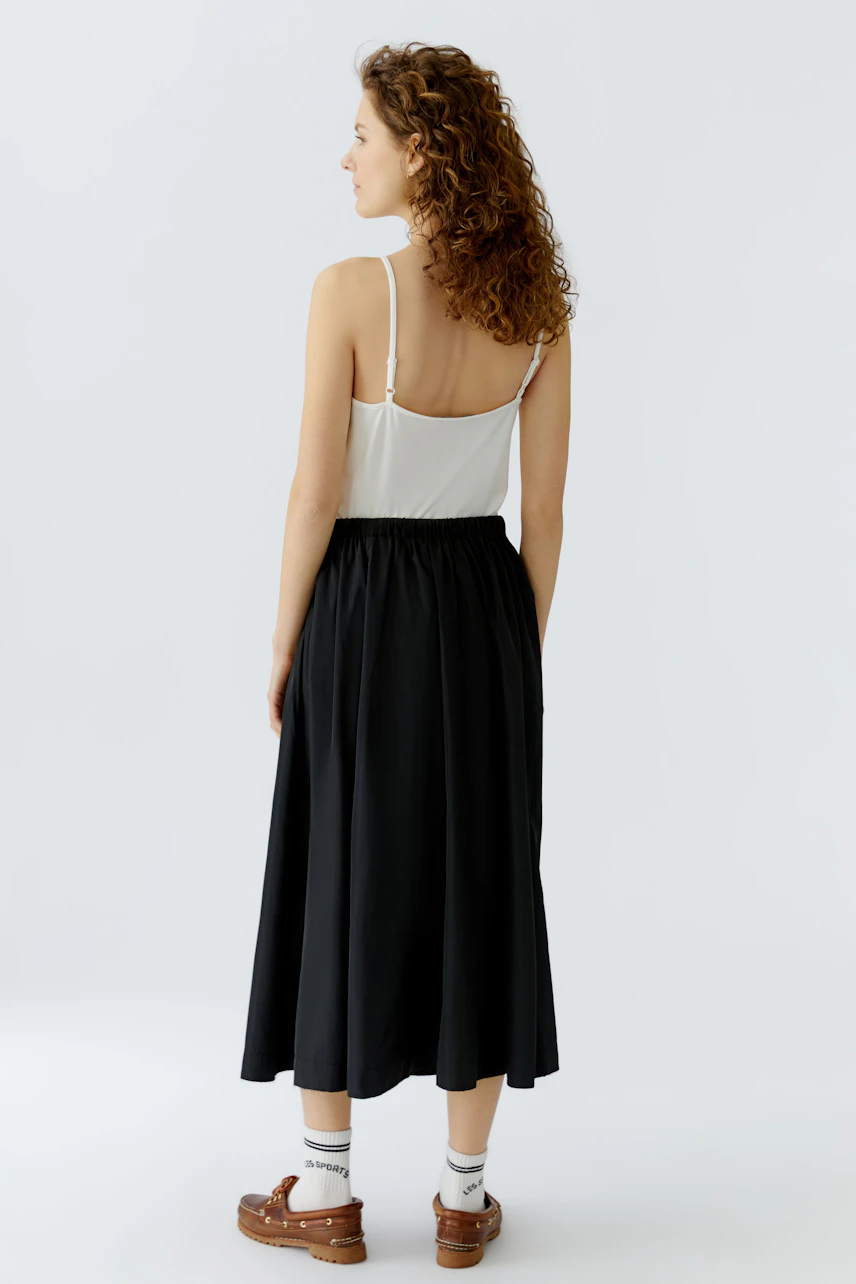 Casual A-line skirt: Woman in a black A-line skirt with a relaxed fit, paired with a simple top.