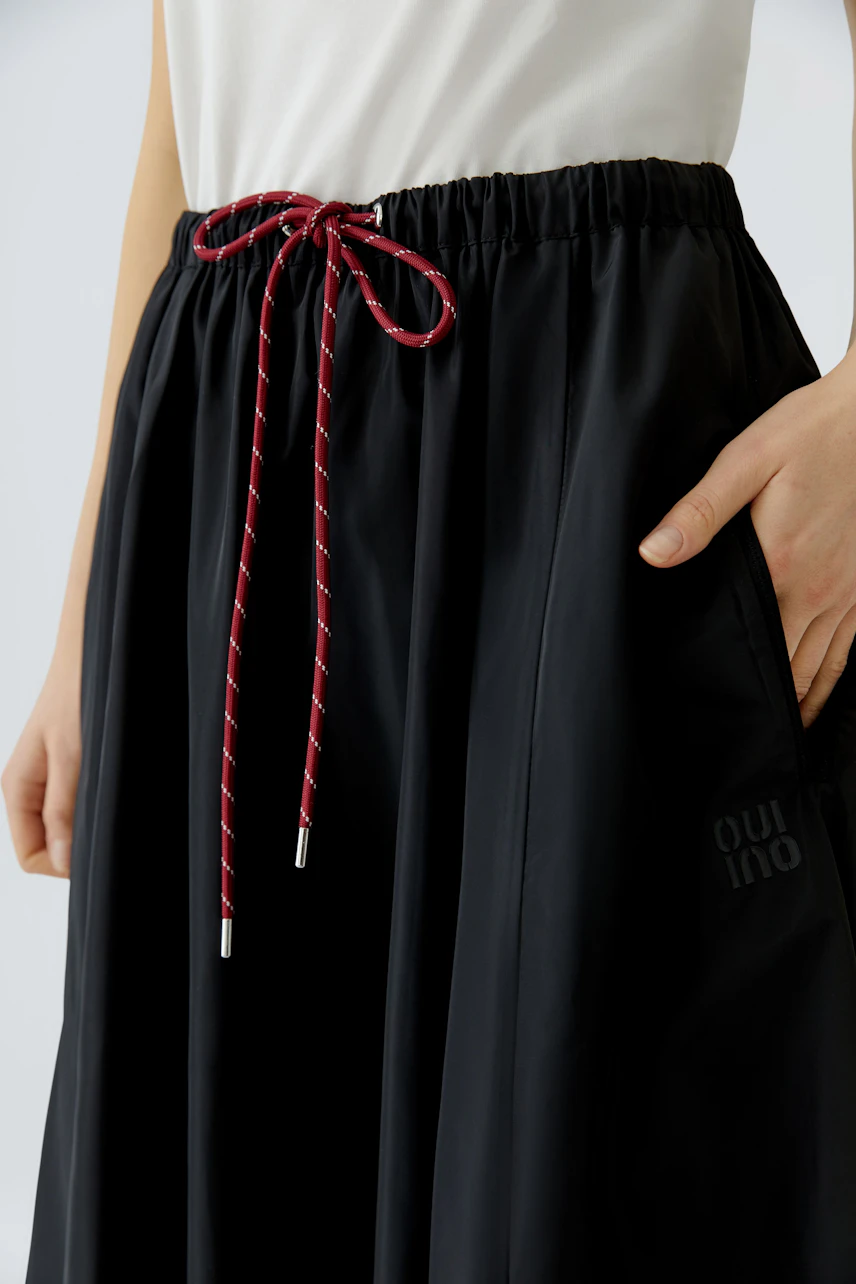 Casual A-line skirt: Woman in a black skirt with a drawstring waist and side pockets.