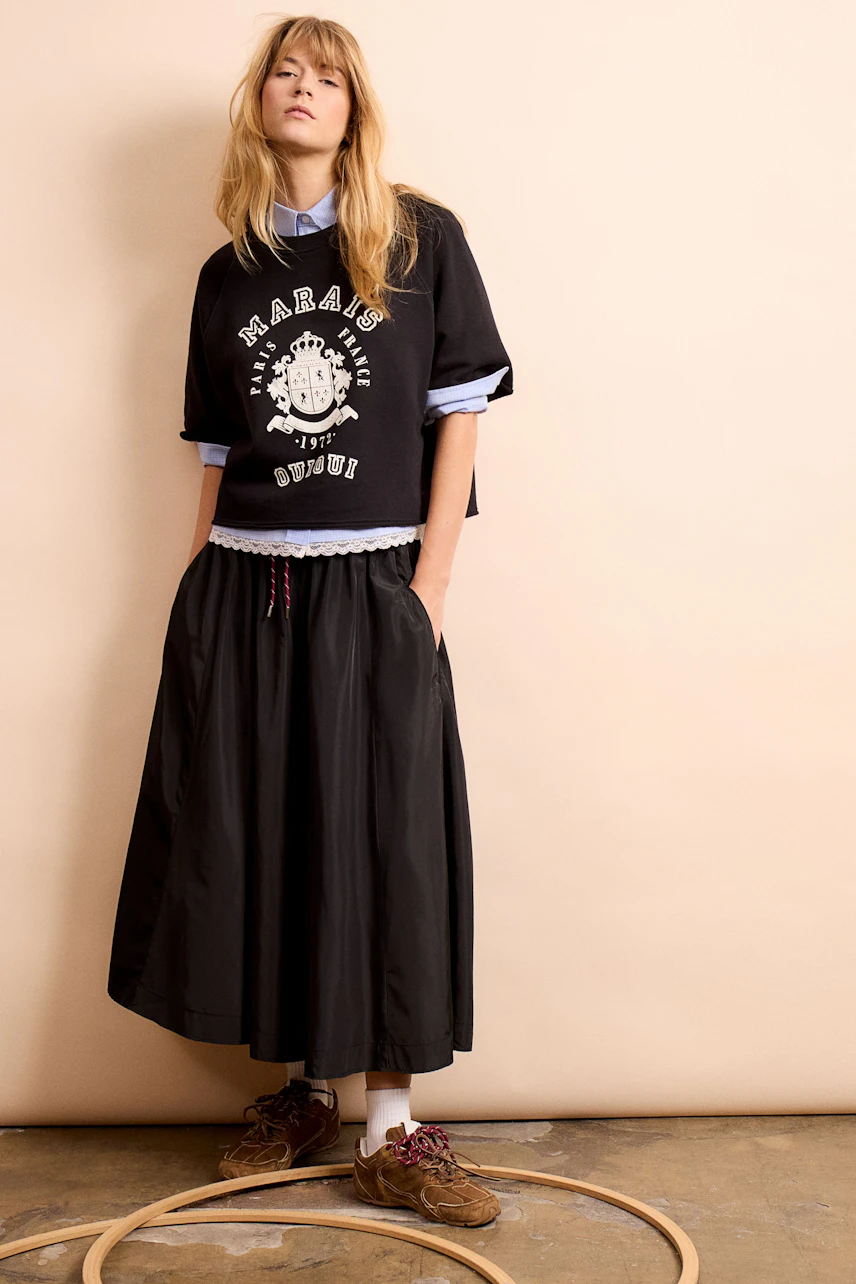 A-line skirt: Young woman in a black A-line skirt paired with a casual pullover and sporty shoes.