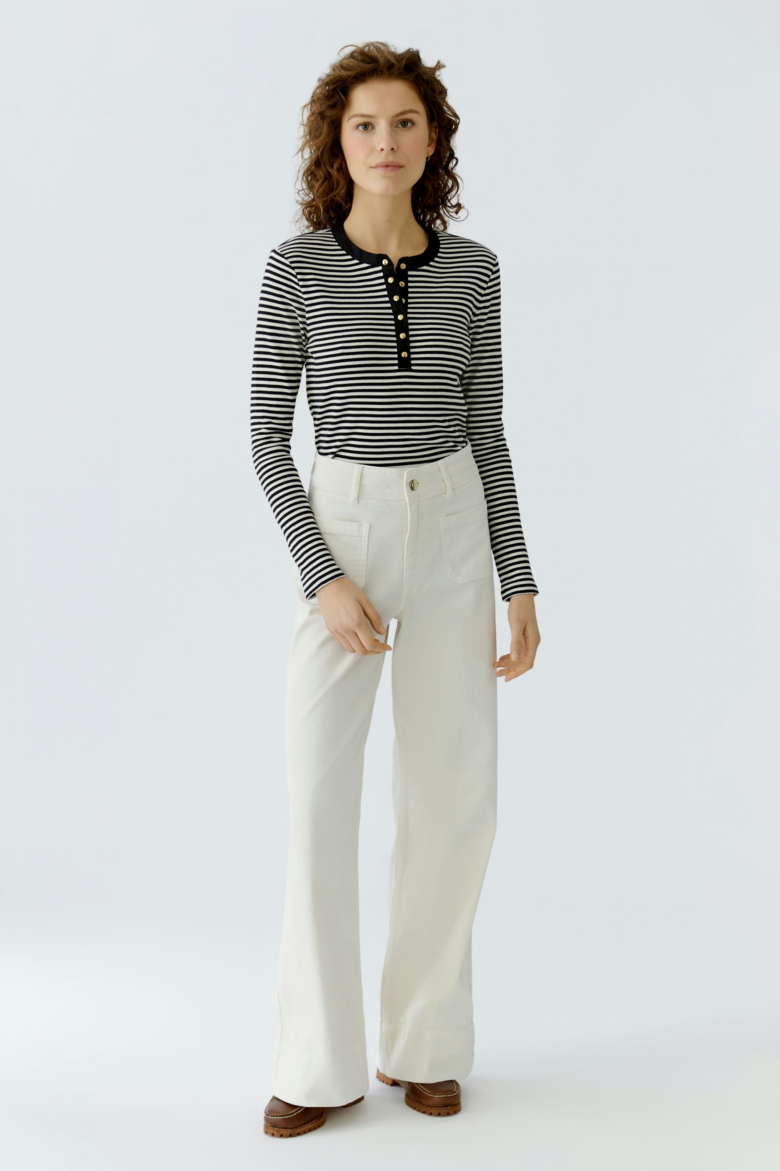 Striped long-sleeve shirt: Woman in a black and white striped pullover with buttons and wide white pants.