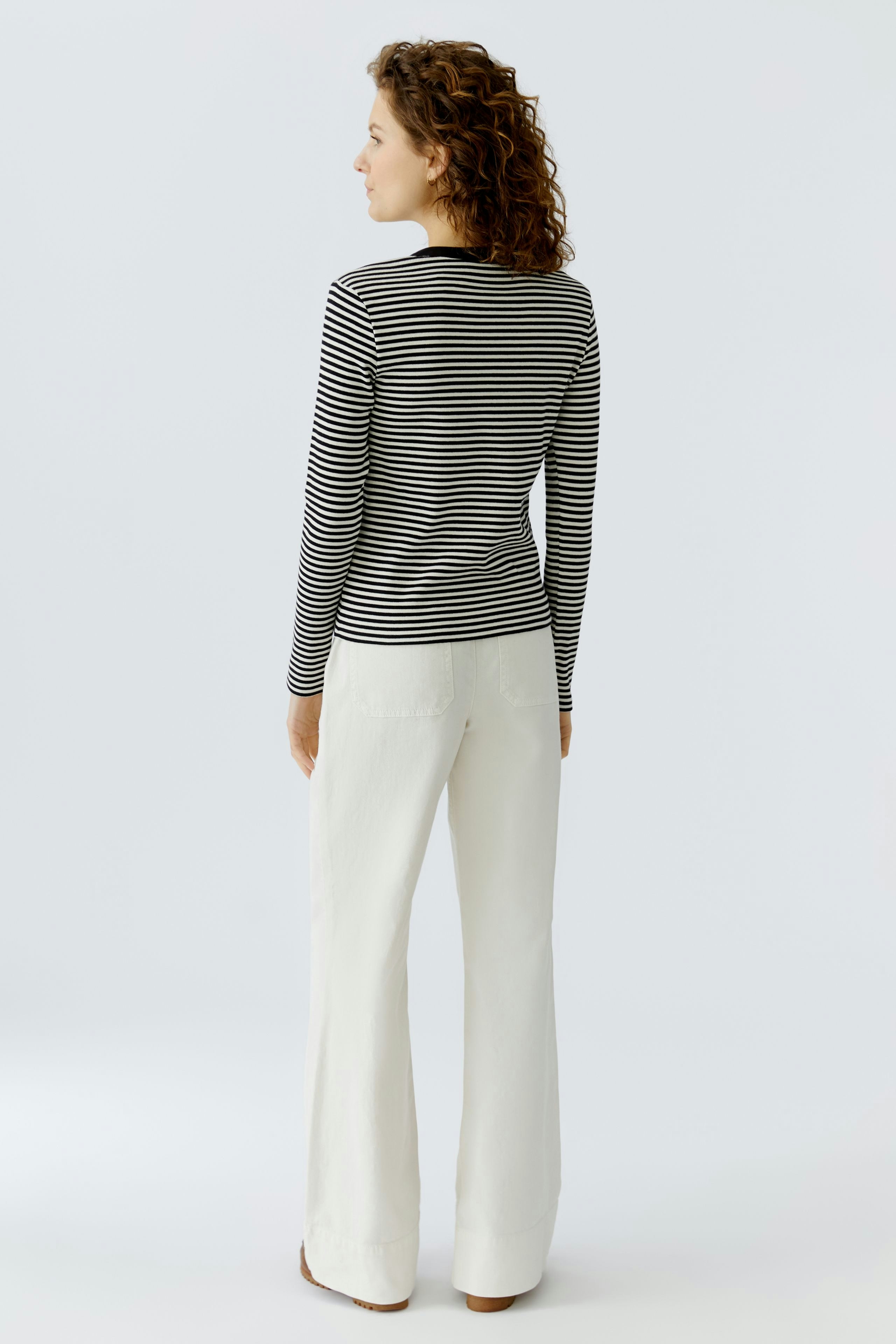 Casual long-sleeve shirt: Woman in a striped pullover, paired with light pants, showcasing a relaxed style.