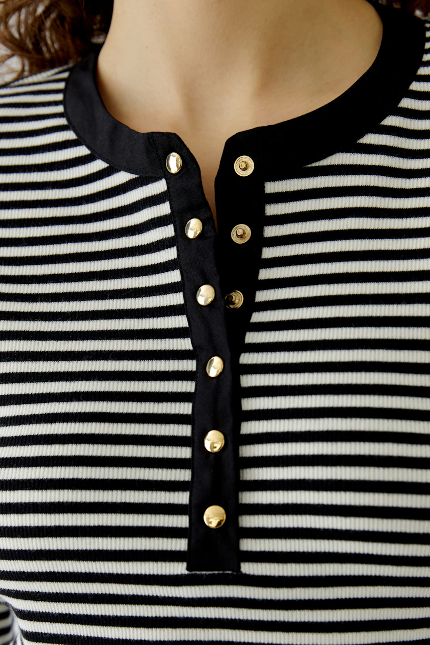 Casual long-sleeve shirt: Close-up of a woman wearing a black and white striped shirt with button details.
