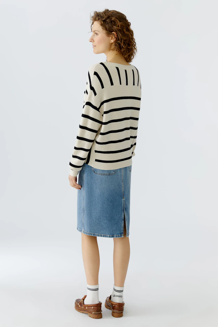 Casual women's pullover: A woman in a striped pullover paired with a denim skirt, showcasing a relaxed style.