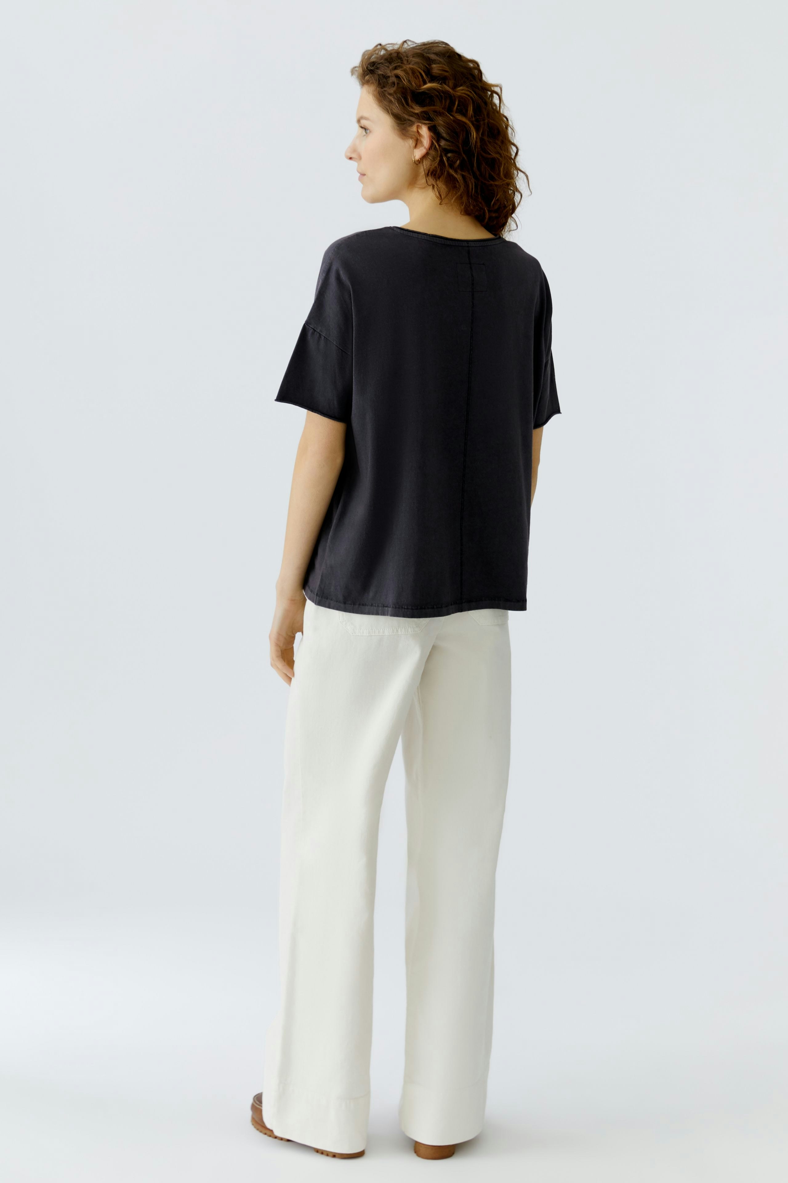 Casual women's T-shirt: A woman in a loose black T-shirt paired with light trousers, showcasing a relaxed style.