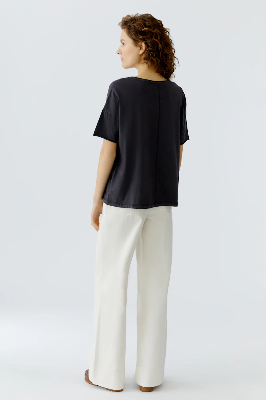Casual women's T-shirt: A woman in a loose black T-shirt paired with light trousers, showcasing a relaxed style.