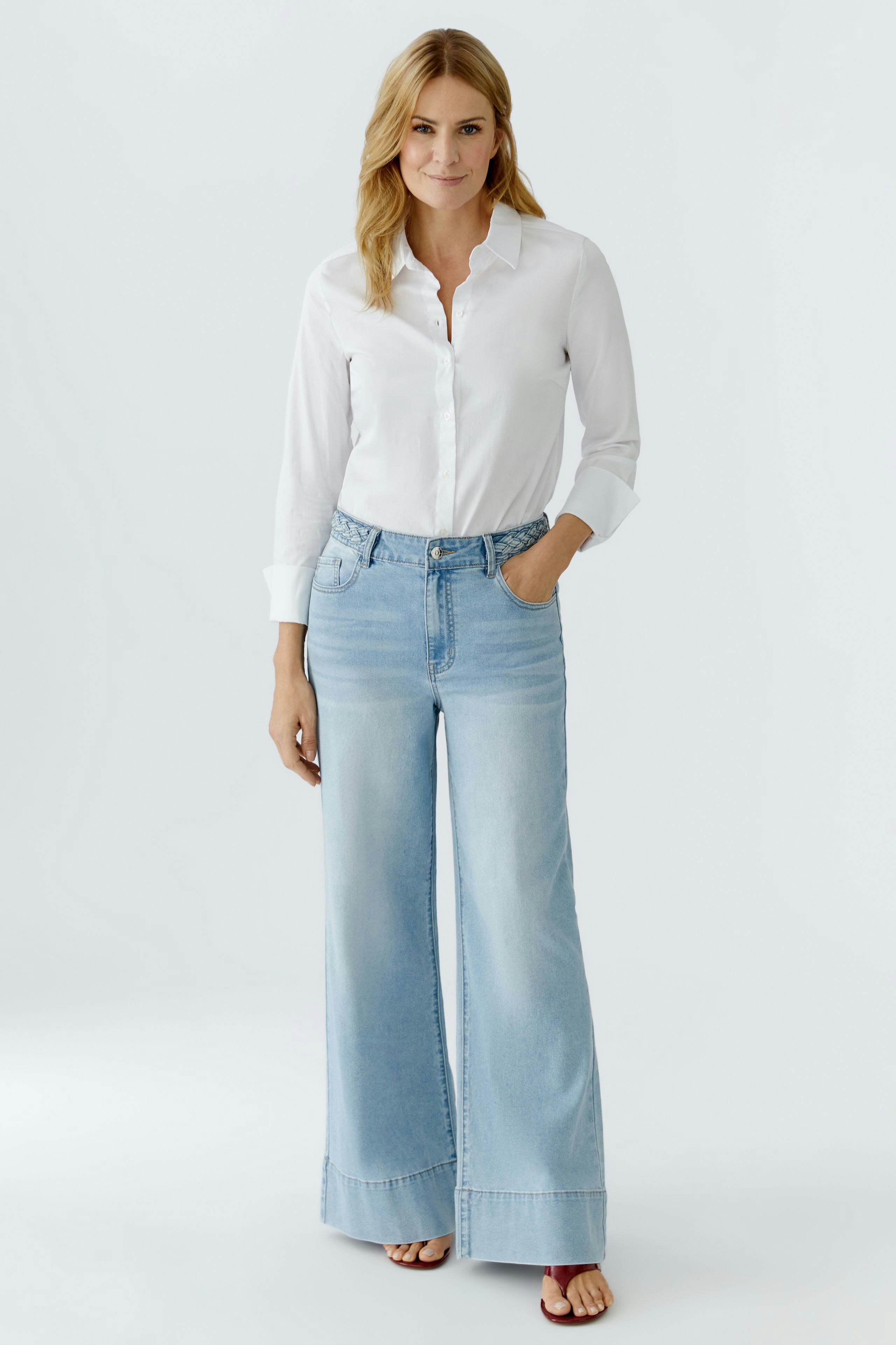 Wide leg jeans: Woman in light blue wide leg jeans paired with a white shirt, showcasing a relaxed style.