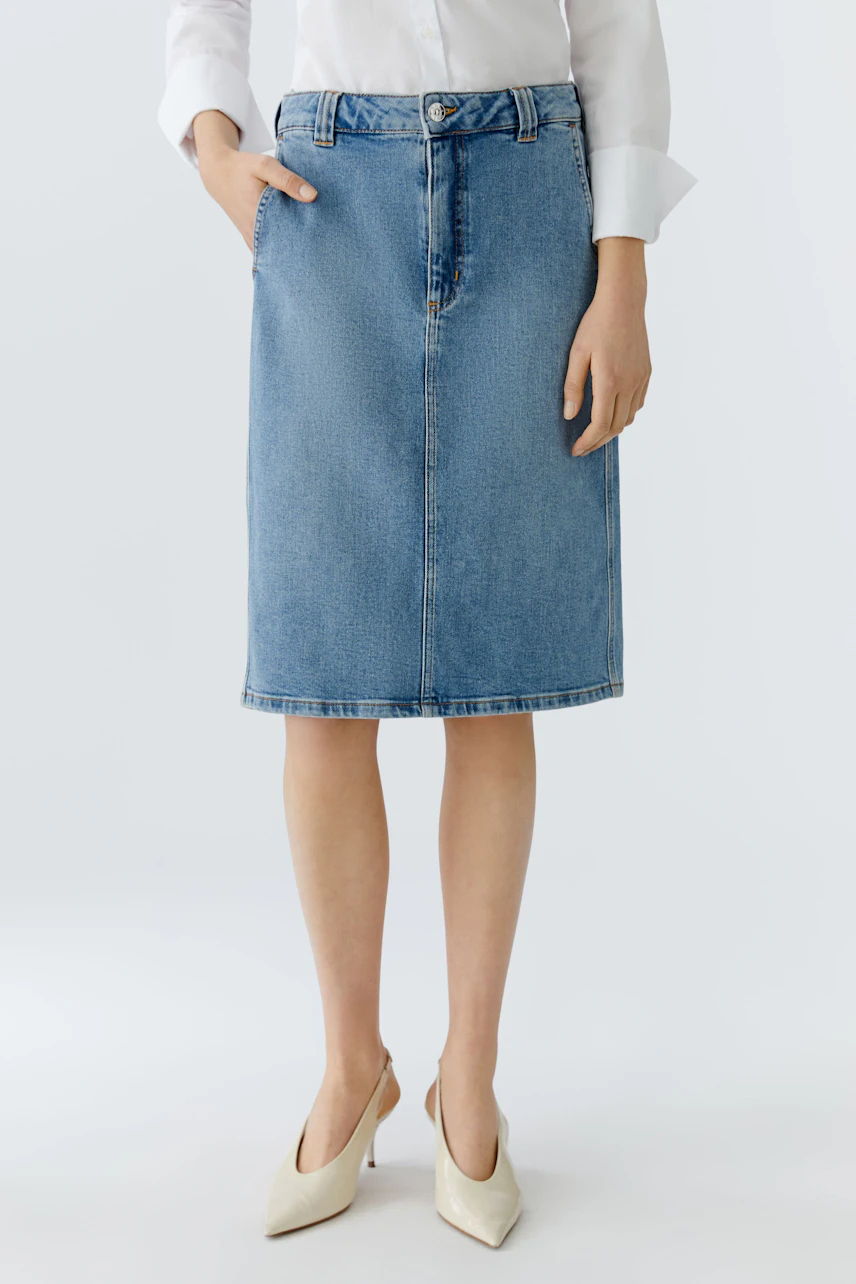 Damen Jeansrock: Frau trägt einen blauen Jeansrock mit geradem Schnitt und praktischen Taschen.