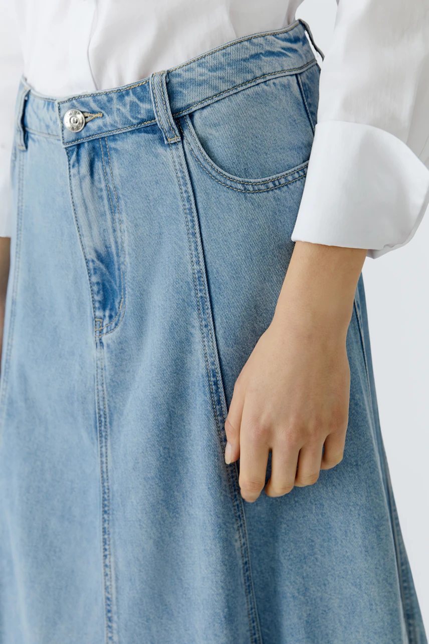 Casual denim skirt: Woman wearing a light blue jeans skirt with a relaxed fit and classic pockets.