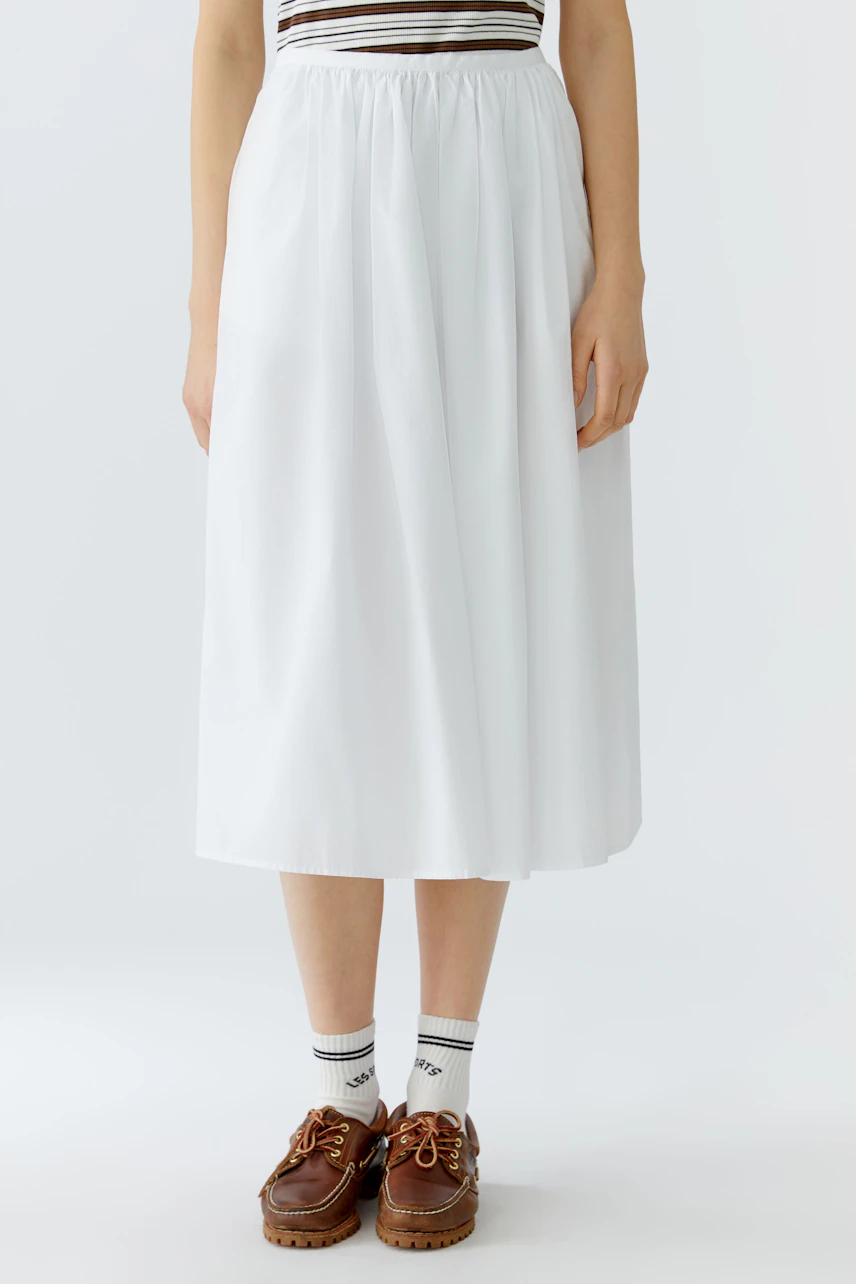 Casual A-line skirt: Woman in a white A-line skirt paired with brown shoes and sporty socks.