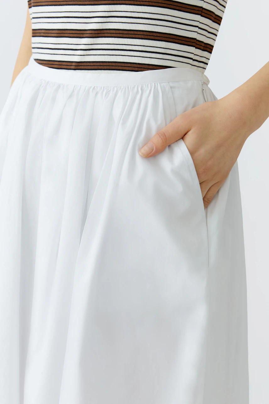 A-line skirt: Woman in a white A-line skirt with pockets, paired with a striped top.