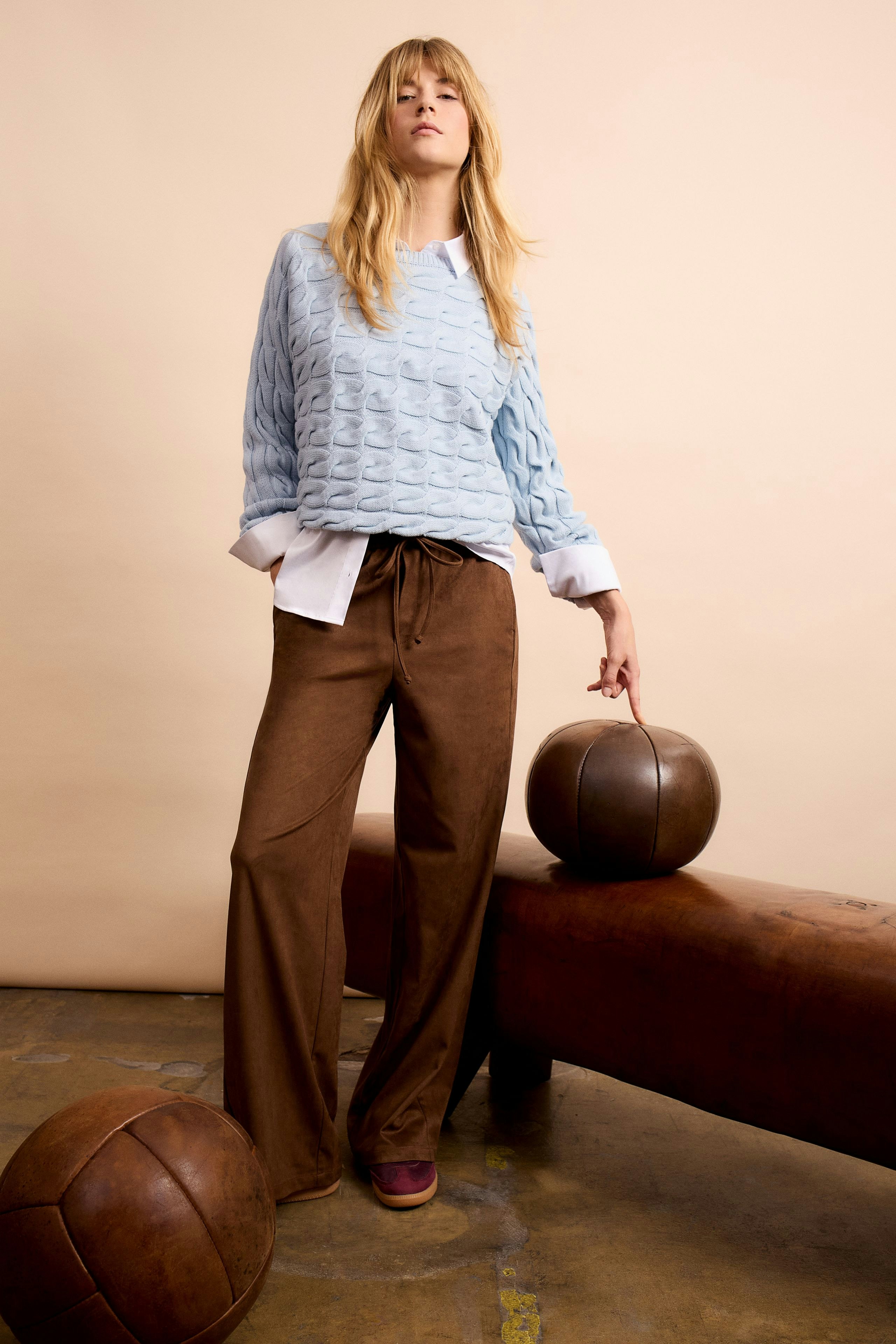 Stylish women's faux leather pants paired with a light blue pullover, exuding a relaxed vibe.
