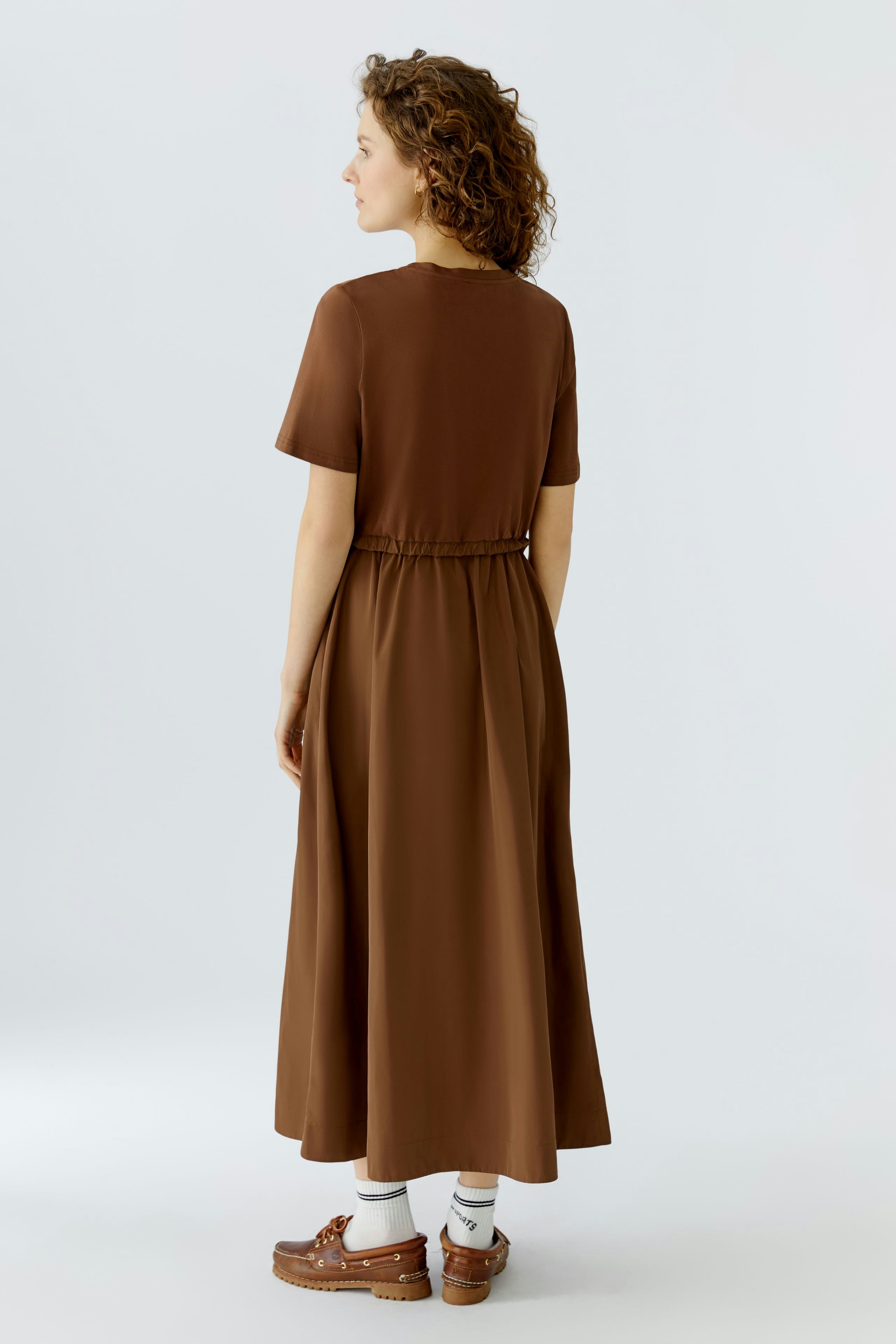 Casual brown maxi dress: Woman in a relaxed fit dress with short sleeves and an elastic waist.