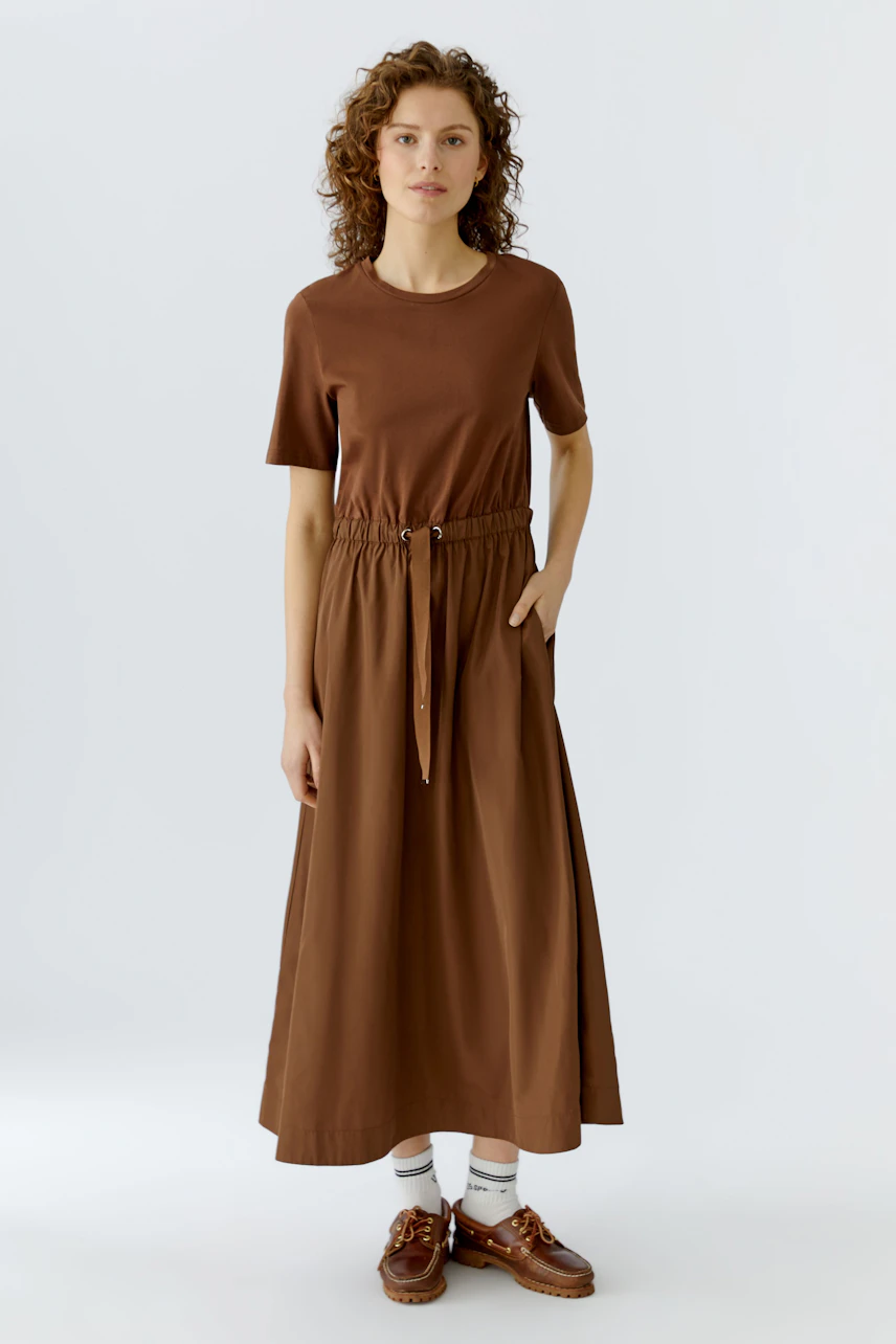Casual brown maxi dress: Woman in a short-sleeve dress with an elastic waist and relaxed fit.